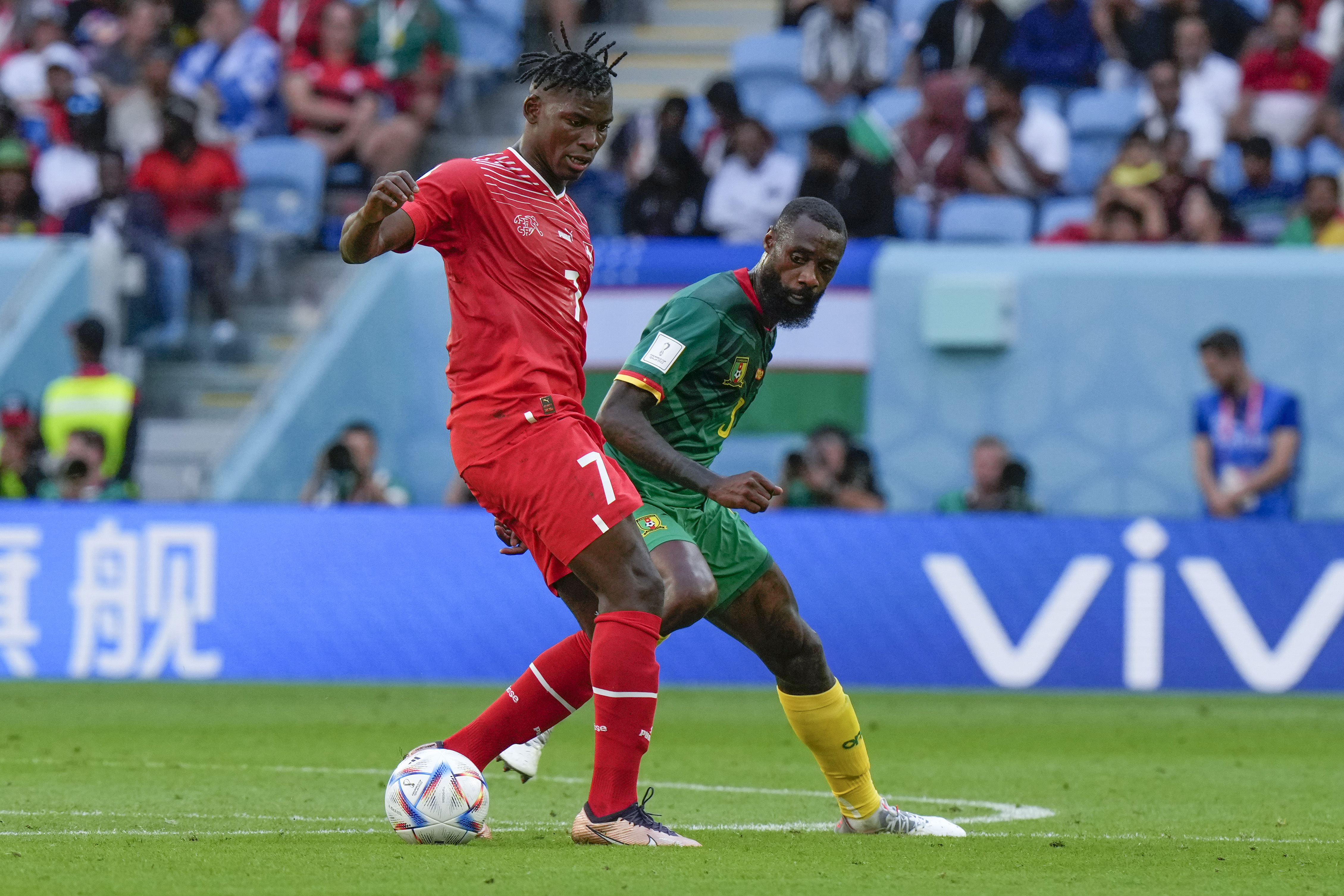 Switzerland's Breel Embolo, left, battles for the ball with Cameroon's Nicolas Nkoulou during the World Cup group G soccer match between Switzerland and Cameroon, at the Al Janoub Stadium in Al Wakrah, Qatar, Thursday, Nov. 24, 2022. (AP Photo/Luca Bruno)