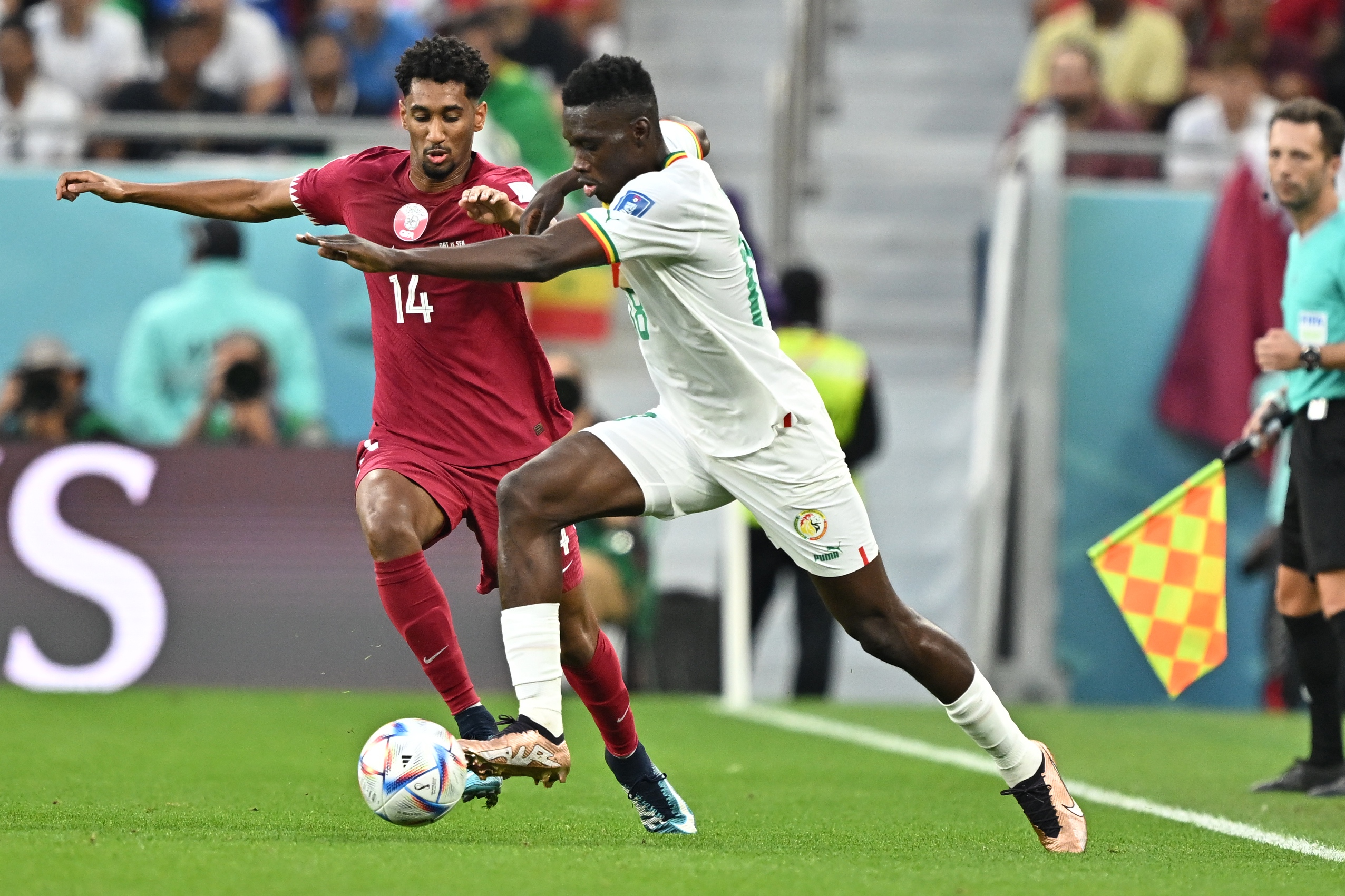 epa10327407 Ismaila Sarr of Sengal in action against Homam Ahmed (L) of Qatar during the FIFA World Cup 2022 group A soccer match between Qatar and Senegal at Al Thumama Stadium in Doha, Qatar, 25 November 2022.  EPA-EFE/Noushad Thekkayil