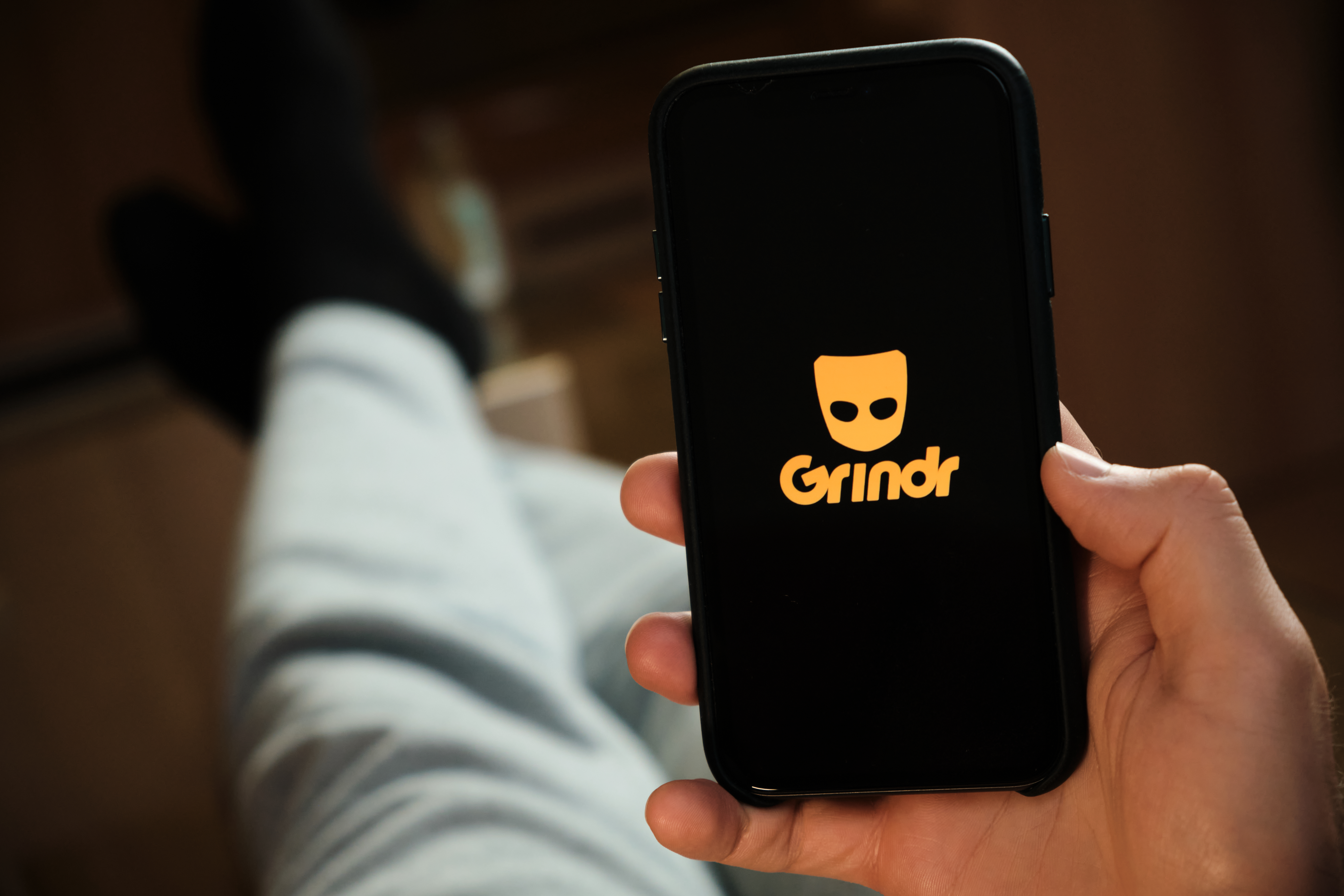 Grindr,Application,On,The,Smartphone,In,Mans,Hand.,Man,Laying