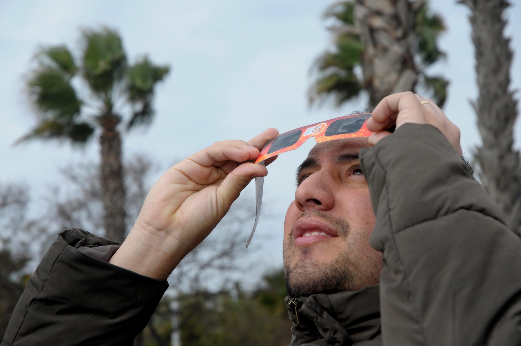 Man with special filtered glasses looking to the solar eclipse, next to Barceloneta beach in Barcelona.