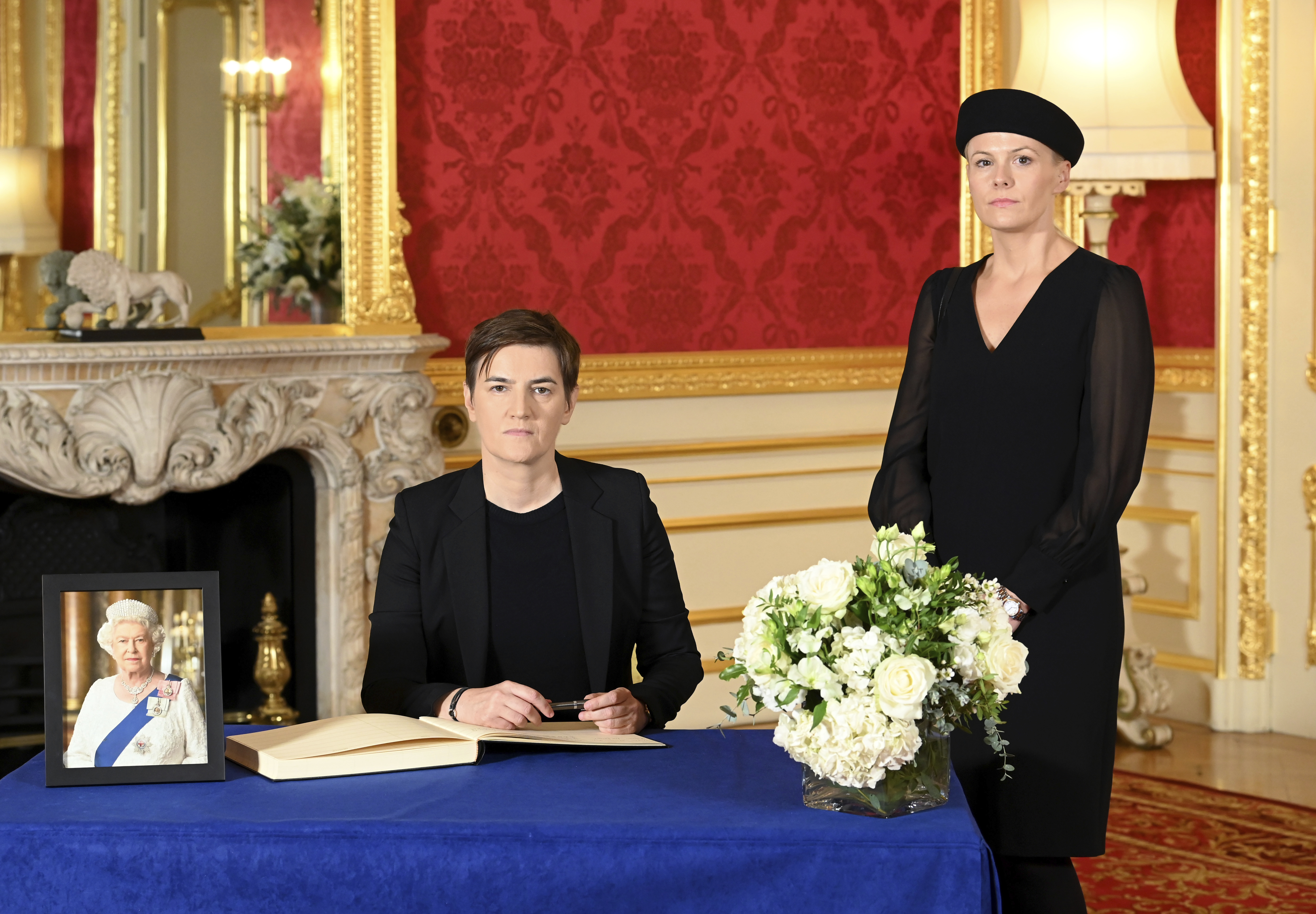 Serbian Prime Minister Ana Brnabic, left, with her partner Milica Durdic signs a book of condolence for Queen Elizabeth II, at Lancaster House in London Sunday, Sept. 18, 2022.  (Jonathan Hordle/Pool Photo via AP)