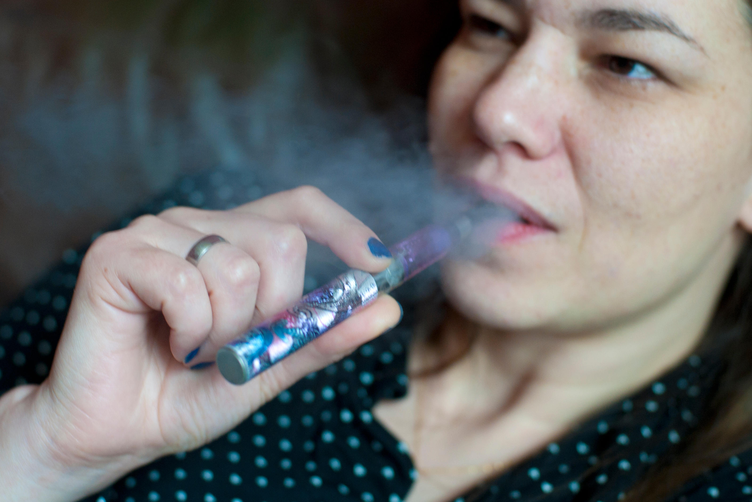 a woman relaxing smoking an e cigarette and blowing out vapour