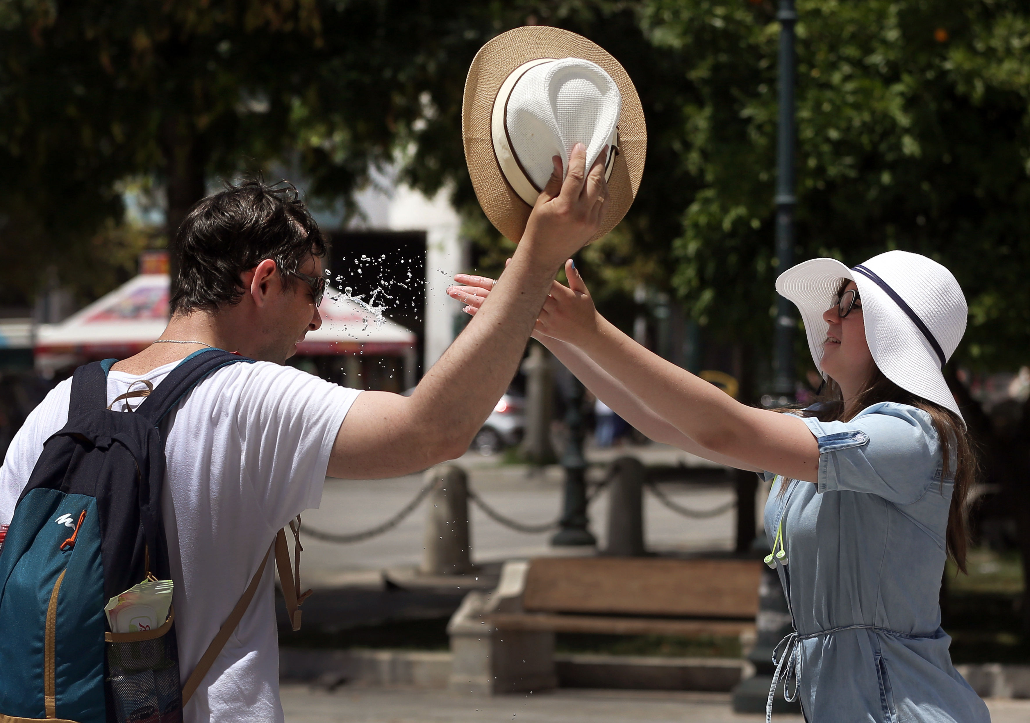 epa06059941 A woman refrehes a man's face with water in central Athens, Greece, 01 July 2017. A heatwave is expected throughout Greece over the weekend with temperatures reaching over 44 degrees Celsius.  EPA/SIMELA PANTZARTZI