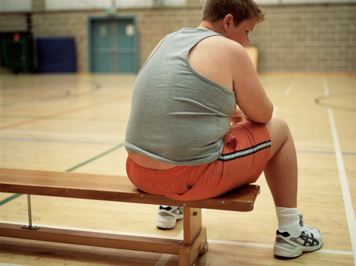 MODEL RELEASED. Overweight boy sat on a bench in a gymnasium, looking tired and depressed.,Image: 102927561, License: Rights-managed, Restrictions: , Model Release: yes, Credit line: GUSTOIMAGES / Sciencephoto / Profimedia