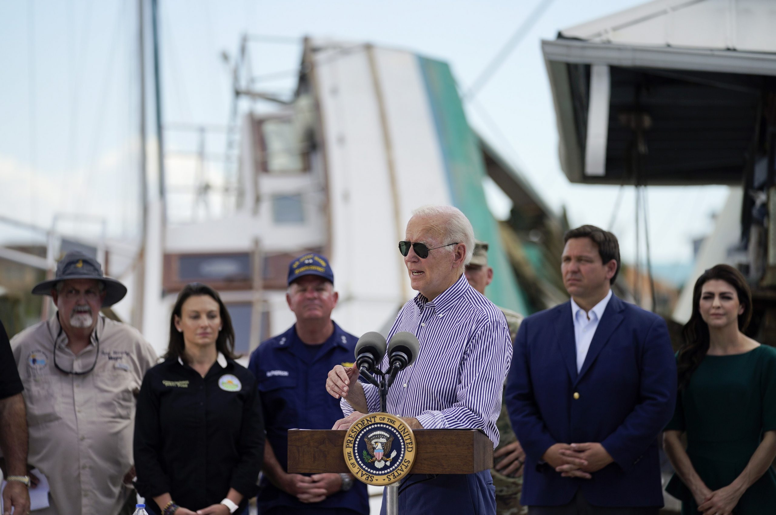 President Joe Biden speaks after touring an area impacted by Hurricane Ian on Wednesday, Oct. 5, 2022, in Fort Myers Beach, Fla. Florida Gov. Ron DeSantis, second from right, and his wife Casey DeSantis listen. (AP Photo/Evan Vucci)