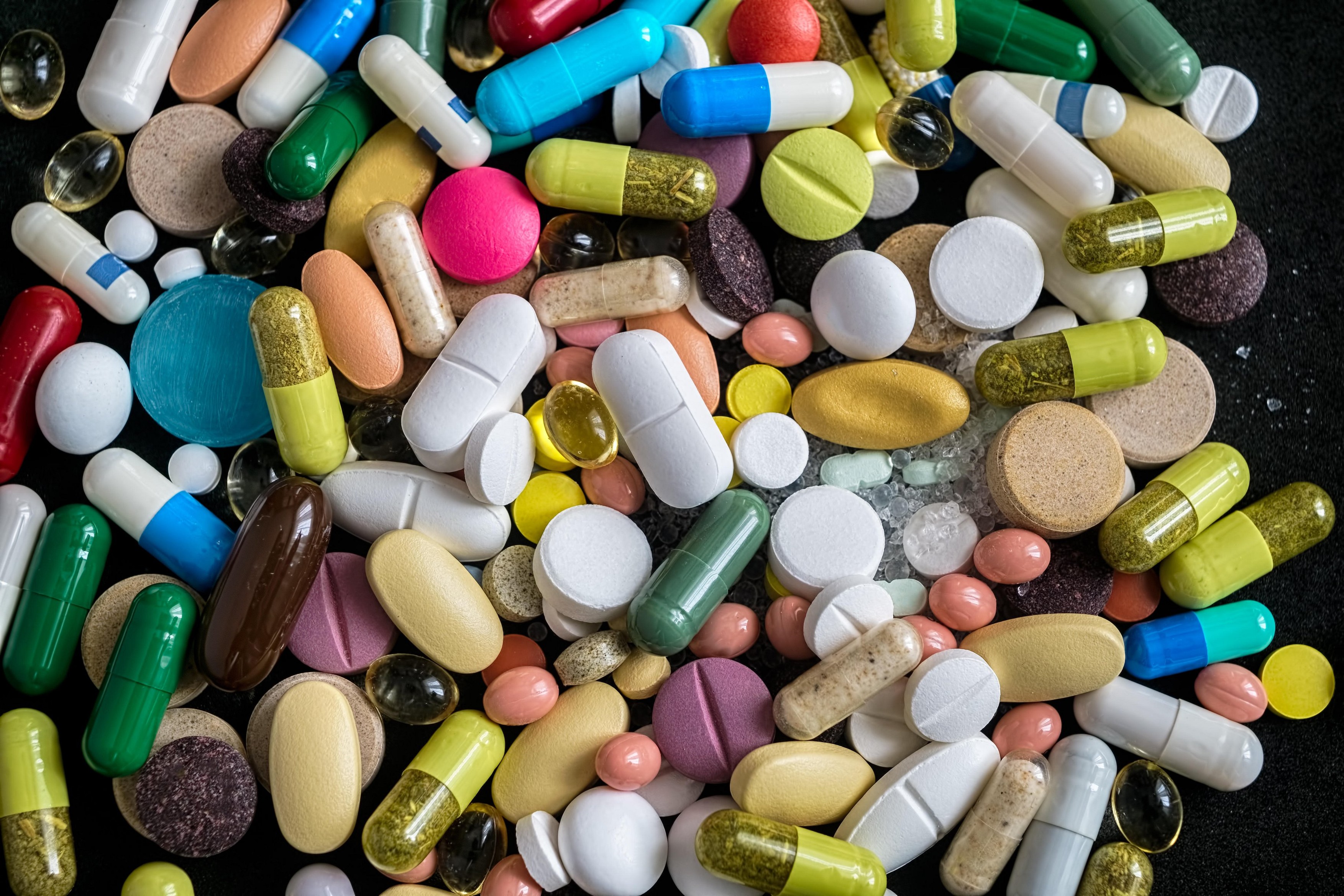 Drugs background.Pharmaceutical tablets, capsules, therapy drugs and pills on black background, top view