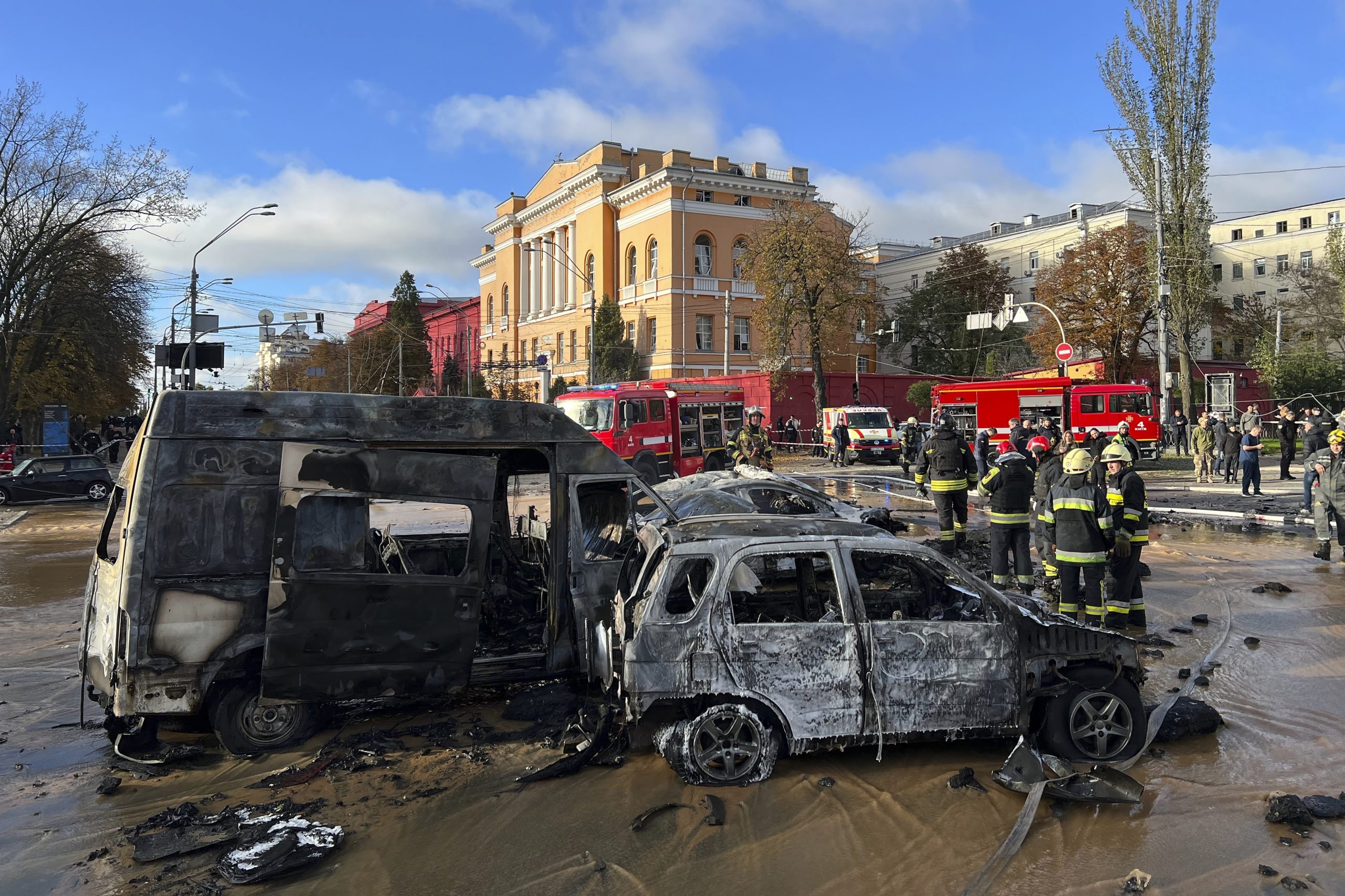 Rescue workers survey the scene of a Russian attack on Kyiv, Ukraine on Monday, Oct. 10, 2022. Two explosions rocked Kyiv early Monday following months of relative calm in the Ukrainian capital. (AP Photo/Adam Schreck)