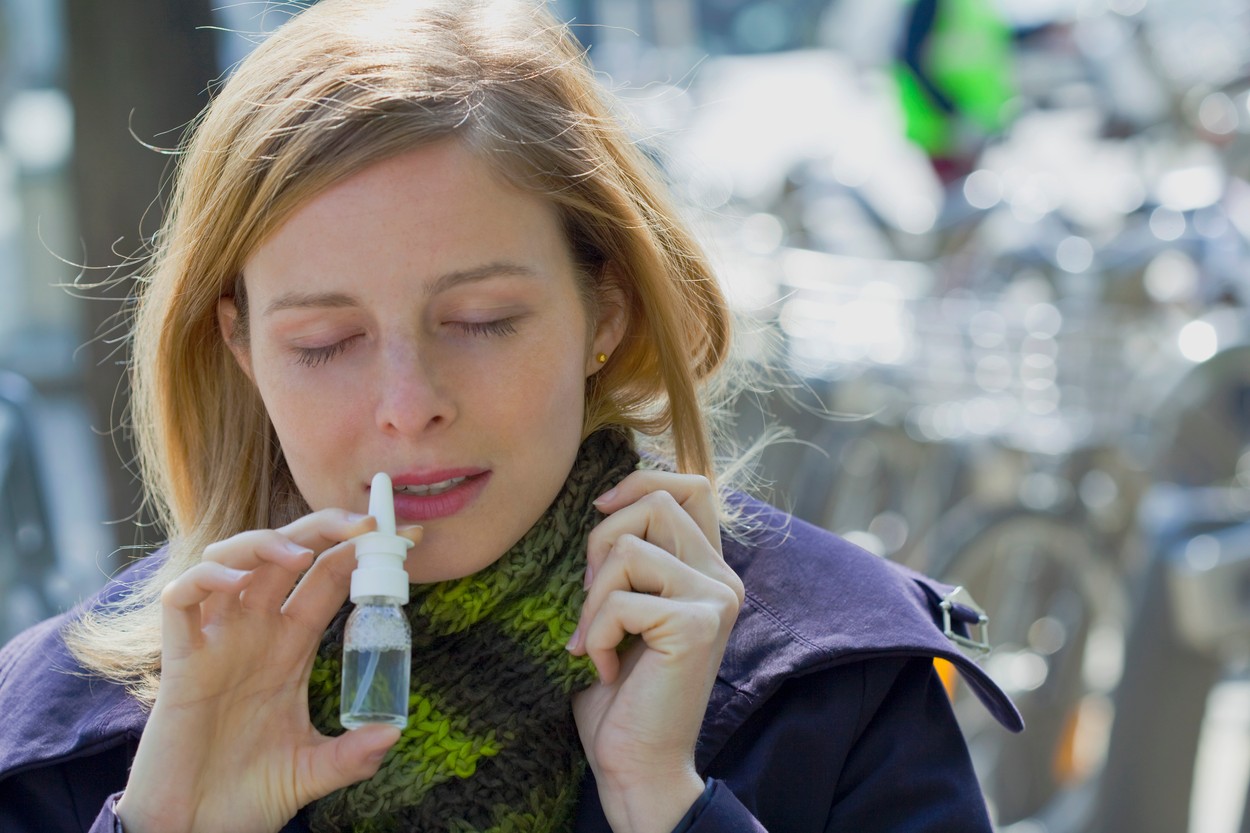 WOMAN USING NOSE SPRAY