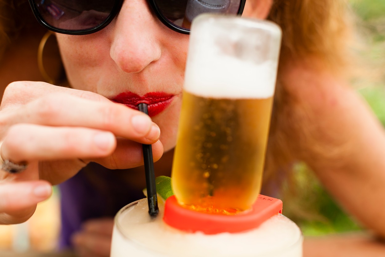 Close up of mid adult woman drinking beer with drinking straw