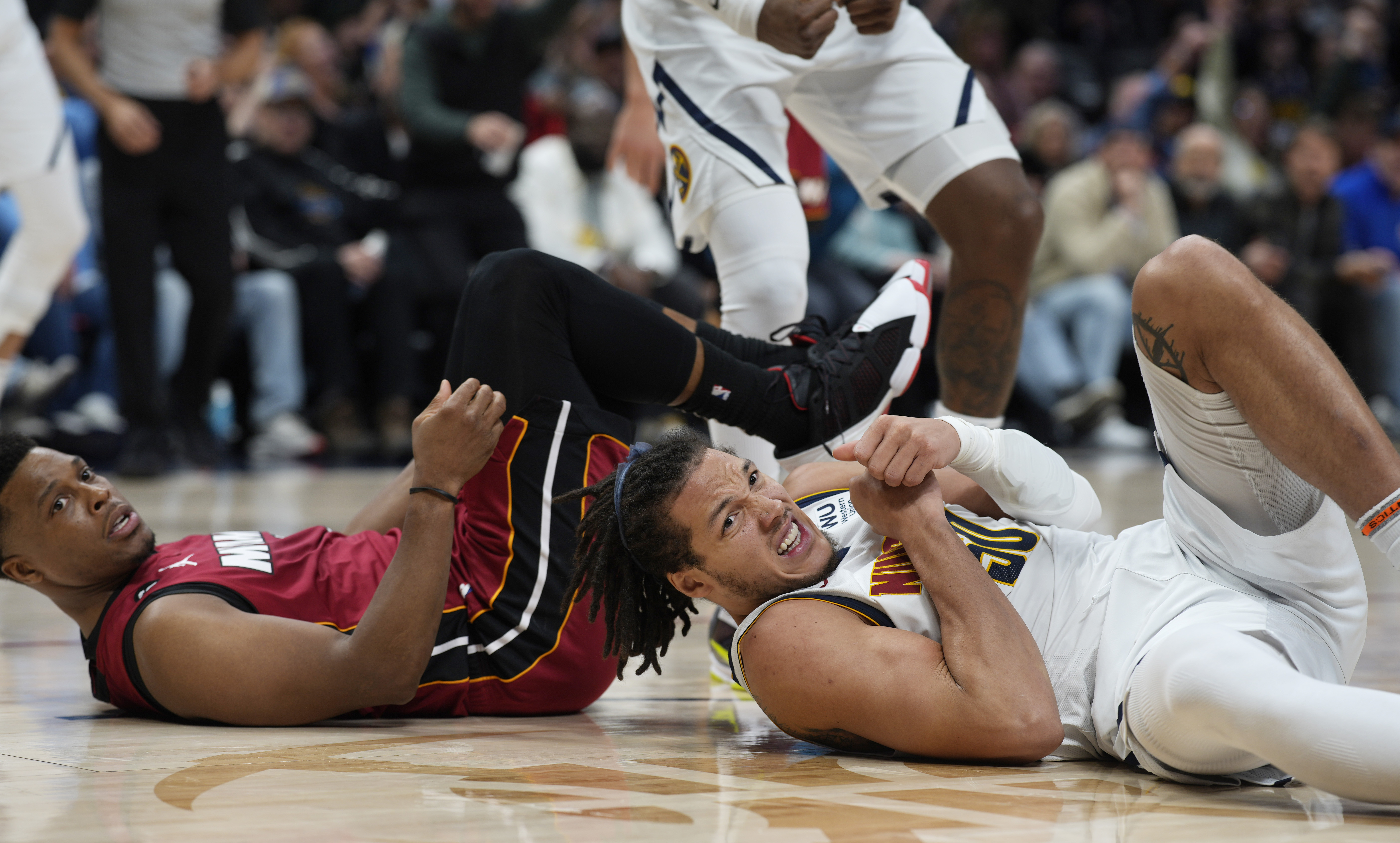 Miami Heat guard Kyle Lowry, left, lands on the floor after fouling Denver Nuggets forward Aaron Gordon, right, in the second half of an NBA basketball game Friday, Dec. 30, 2022, in Denver. (AP Photo/David Zalubowski)