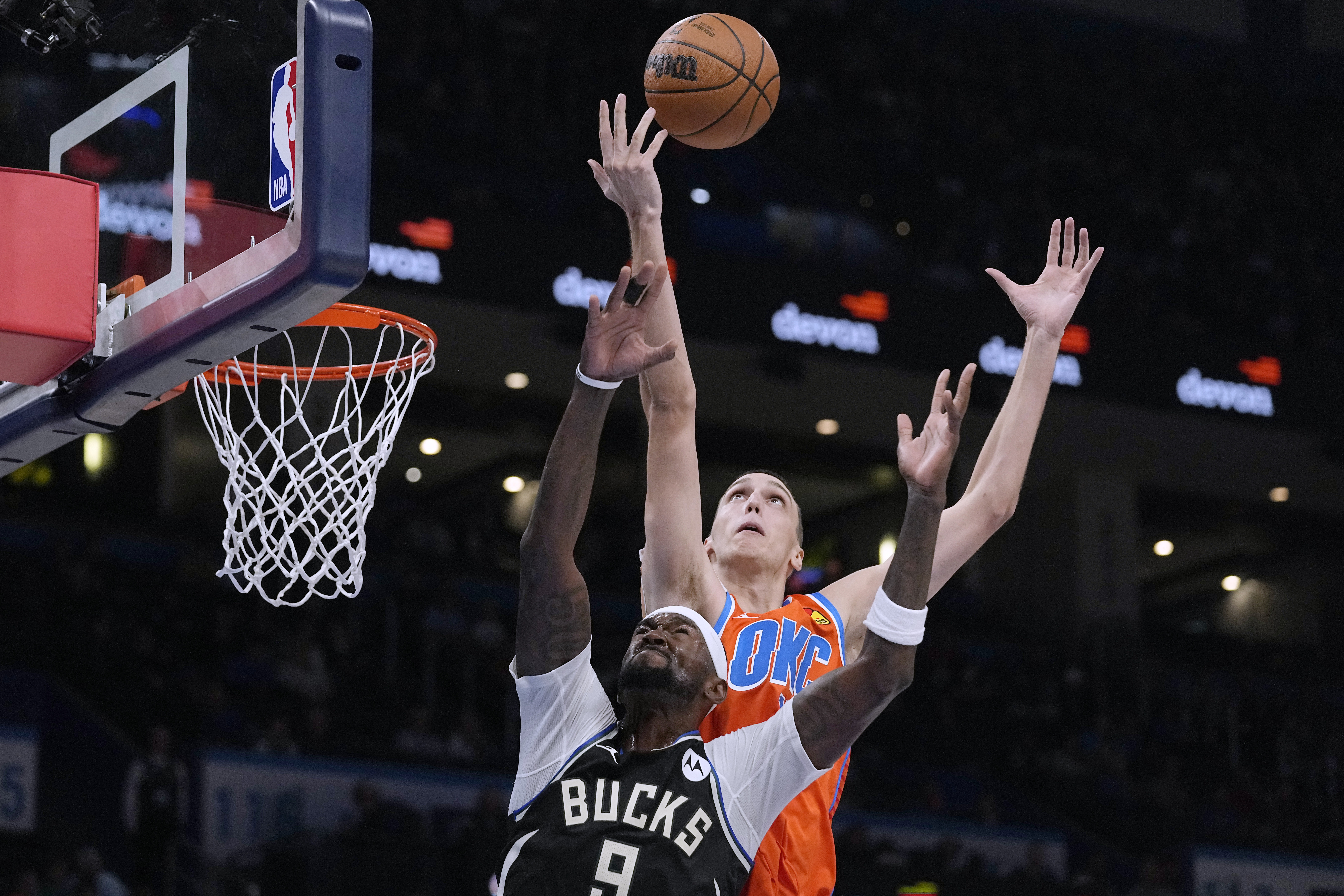 Oklahoma City Thunder forward Aleksej Pokusevski, rear, reaches for a rebound over Milwaukee Bucks forward Bobby Portis (9) during the first half of an NBA basketball game Wednesday, Nov. 9, 2022, in Oklahoma City. (AP Photo/Sue Ogrocki)