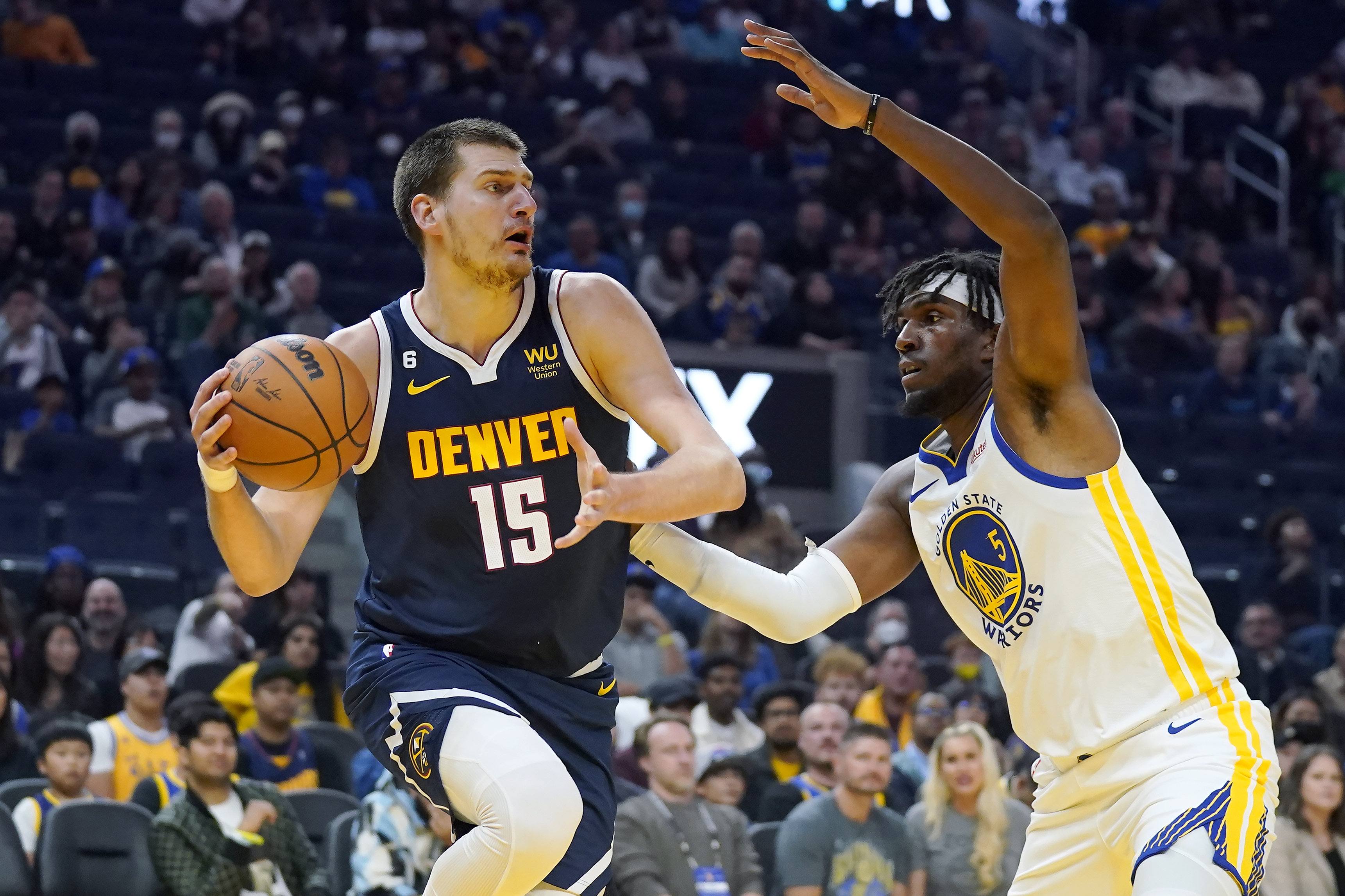 Denver Nuggets center Nikola Jokic (15) looks to pass the ball against Golden State Warriors center Kevon Looney (5) during the first half of an NBA preseason basketball game in San Francisco, Friday, Oct. 14, 2022. (AP Photo/Jeff Chiu)