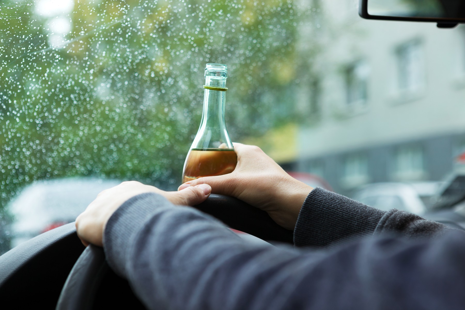 Drunk young driver drinking a bottle of wine during driving the