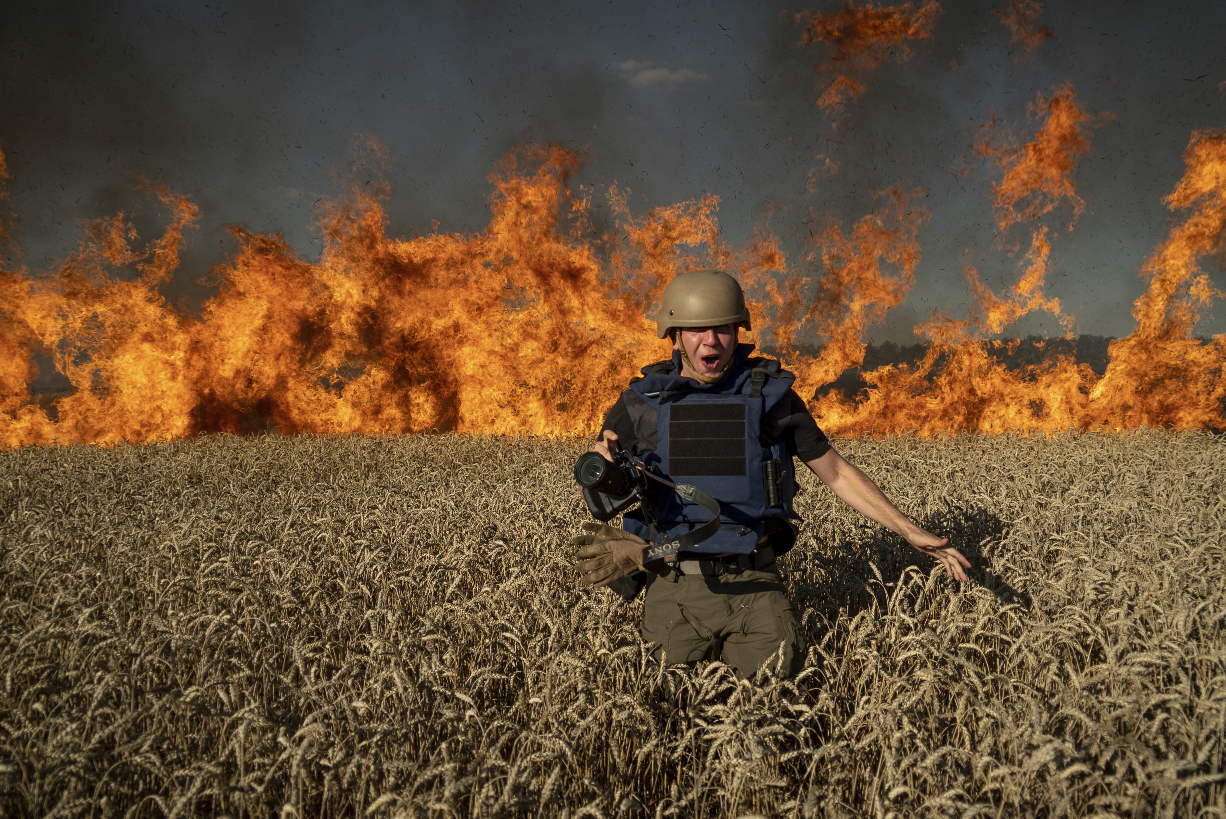 Photojournalist Evgeniy Maloletka runs from the fire in a burning wheat field during his assignment after Russian shelling, a few kilometres from Ukrainian-Russian border in the Kharkiv region, Ukraine, Friday, July 29, 2022. (AP Photo/Mstyslav Chernov)