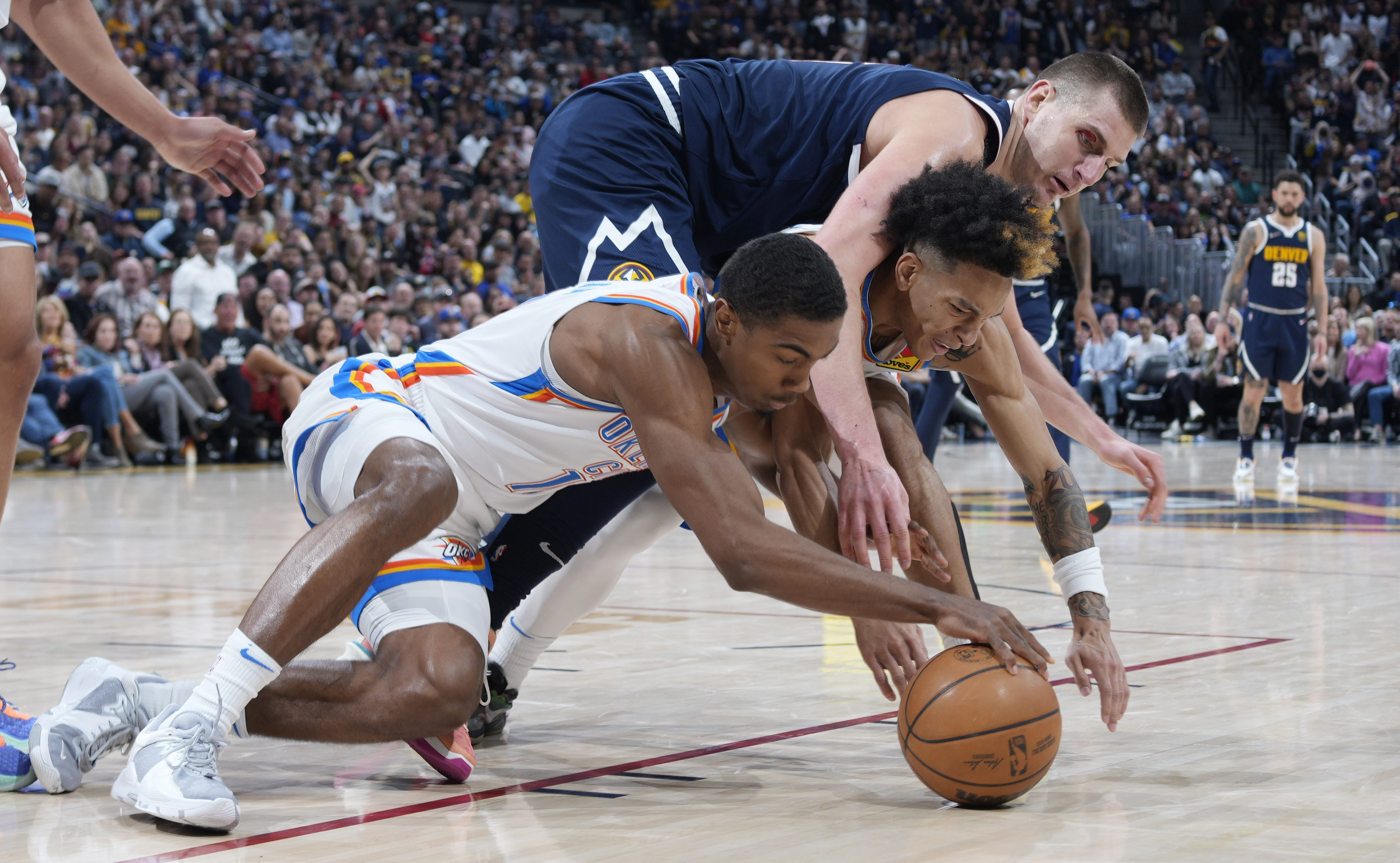 Oklahoma City Thunder guards Theo Maledon, left, and Tre Mann and Denver Nuggets center Nikola Jokic vie for control of the ball during the second half of an NBA basketball game Saturday, March 26, 2022, in Denver. (AP Photo/David Zalubowski)