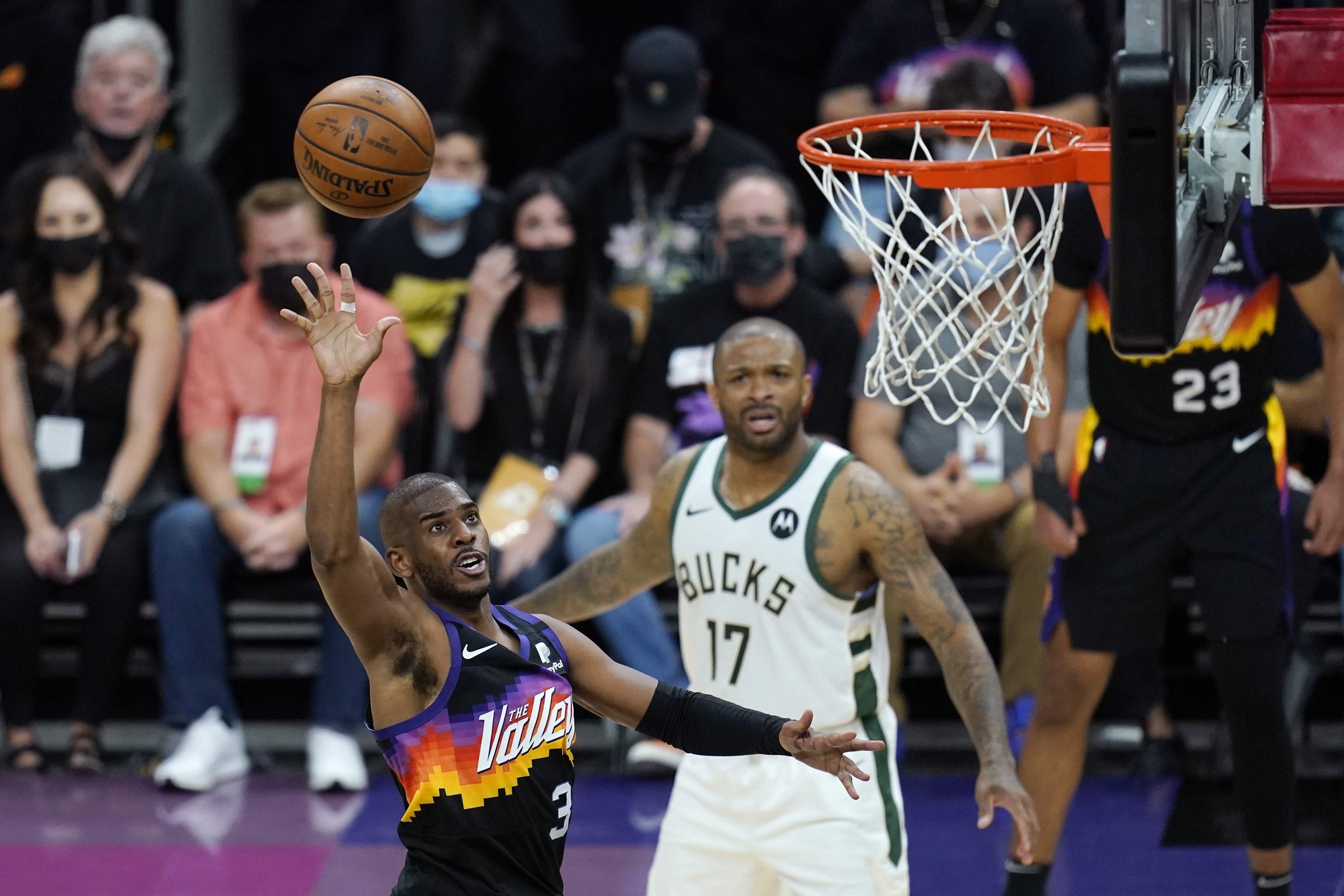 Phoenix Suns guard Chris Paul (3) scores as Milwaukee Bucks forward P.J. Tucker (17) looks on during the second half of Game 1 of basketball's NBA Finals, Tuesday, July 6, 2021, in Phoenix. The Suns defeated the Bucks 118-105. (AP Photo/Ross D. Franklin)