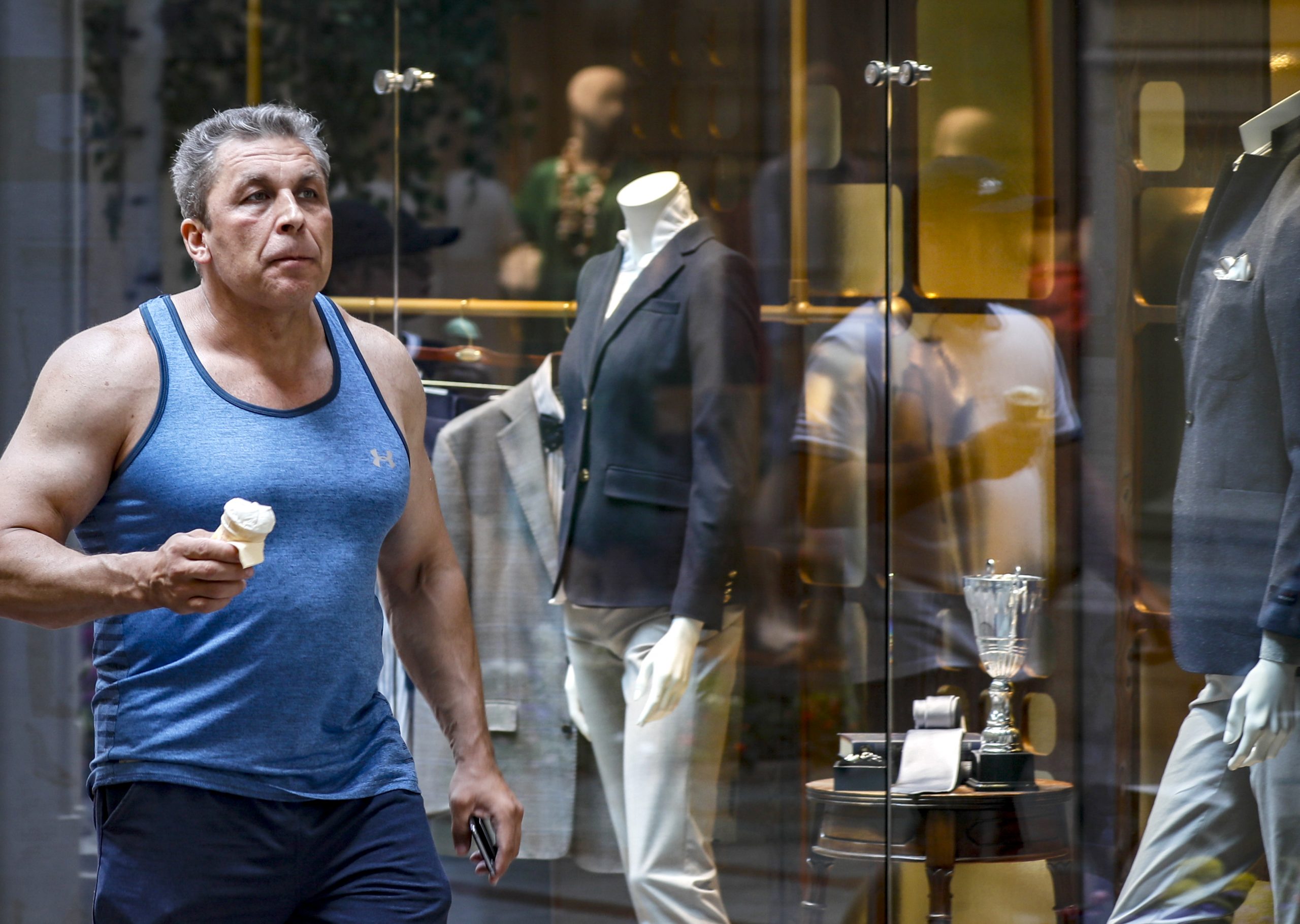epa10045787 A man eating an ice cream walks past a shop window at the GUM department store in Moscow, Russia, 01 July 2022.  EPA-EFE/YURI KOCHETKOV