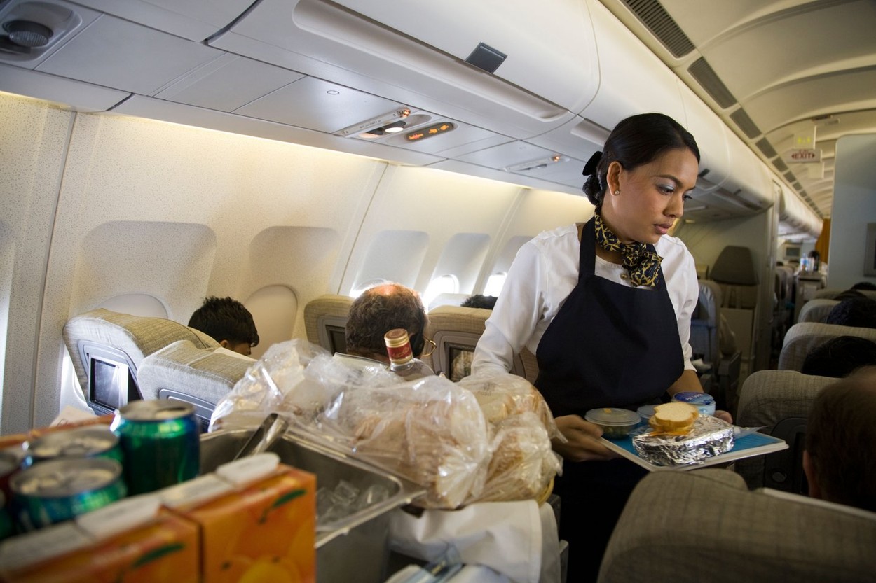 Cabin crew / air stewardess serves a meal tray to a passenger from a trolley cart during a flight (45),Image: 34715269, License: Rights-managed, Restrictions: , Model Release: no, Credit line: Credit / / Alamy / Profimedia