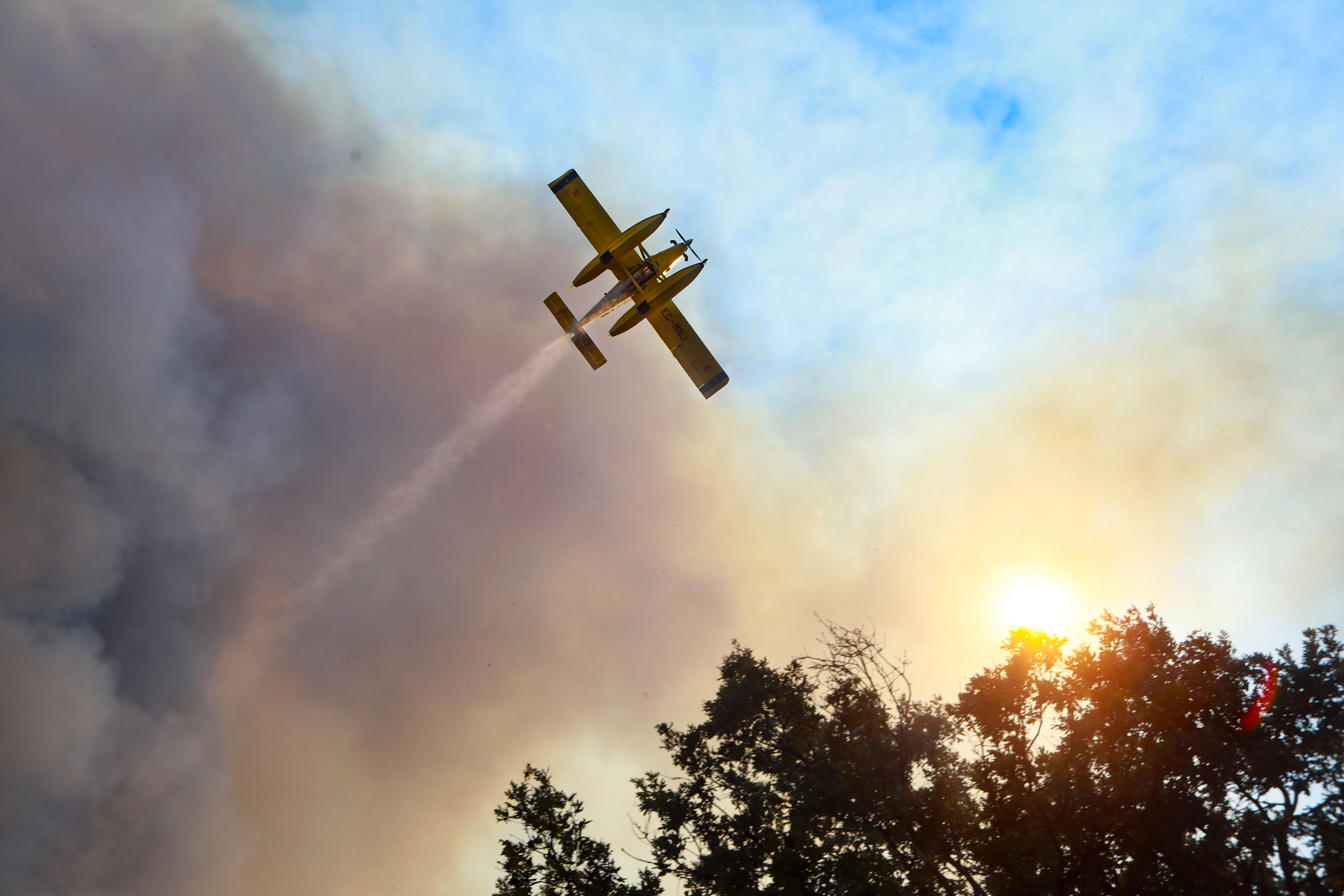 epa10057593 An airplane drops water over a forest fire in Benespera, Guarda, northern Portugal, 07 July 2022. 325 operational, 96 vehicles and 4 airplane are fighting the forest fire.  EPA-EFE/MIGUEL PEREIRA DA SILVA