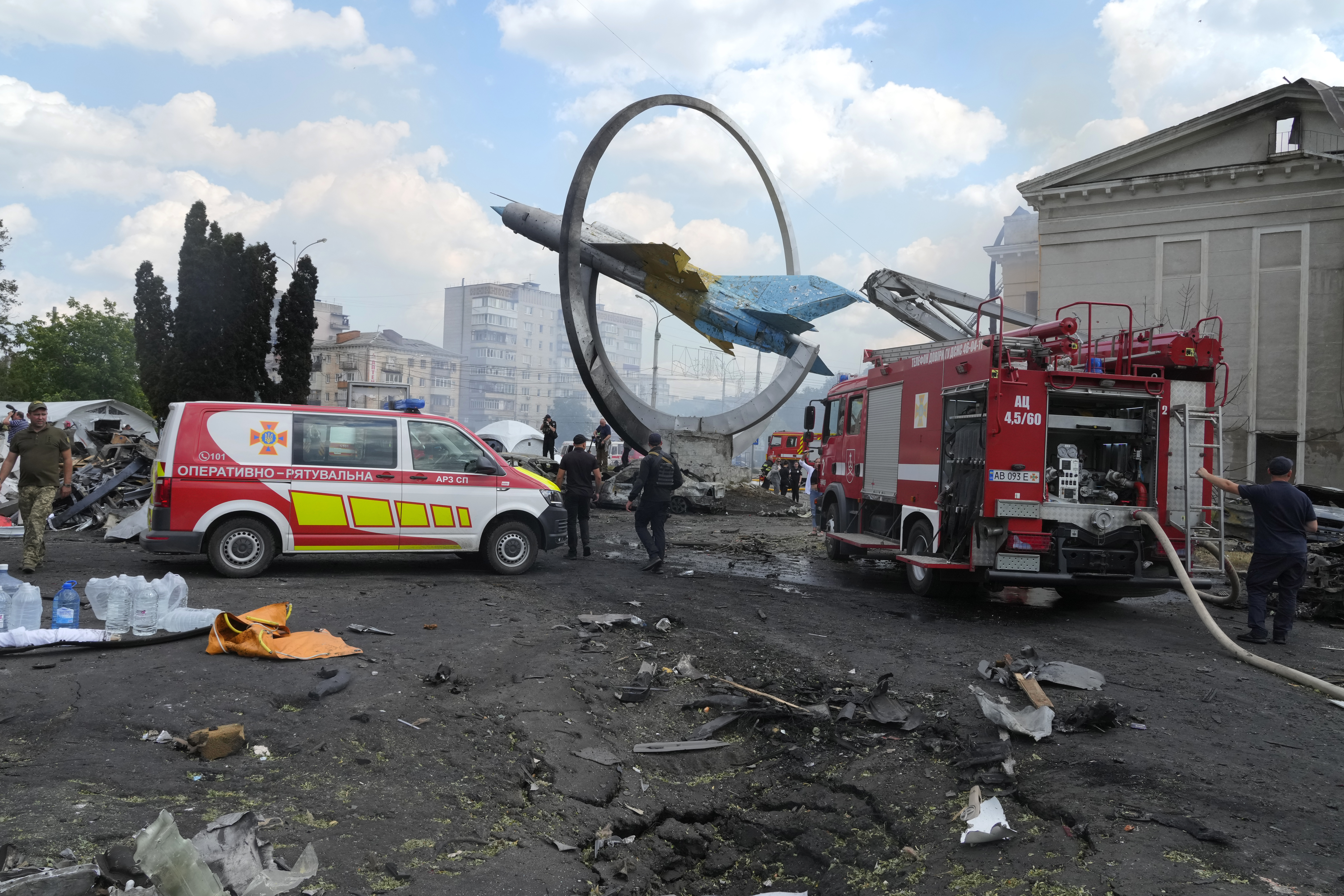 Rescuers work at the scene of a building that was damaged by a deadly Russian missile attack next to a monument in honor of the Ukrainian Air Force with a Soviet MiG-21 fighter jet, in Vinnytsia, Ukraine, Thursday, July 14, 2022. (AP Photo/Efrem Lukatsky)