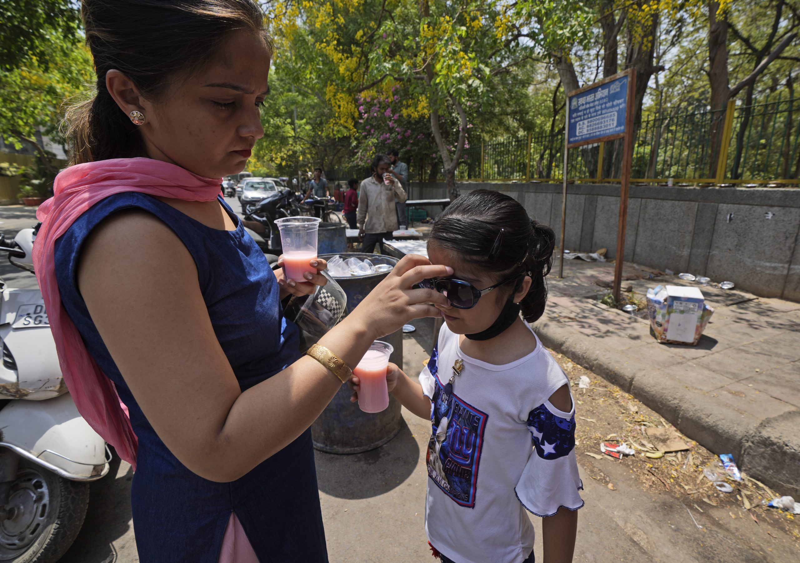 A woman puts on a sunglass for her child on a hot day in New Delhi, Saturday, May 14, 2022. The temperature in New Delhi reached 45 Degrees Celsius. (AP Photo/Manish Swarup)