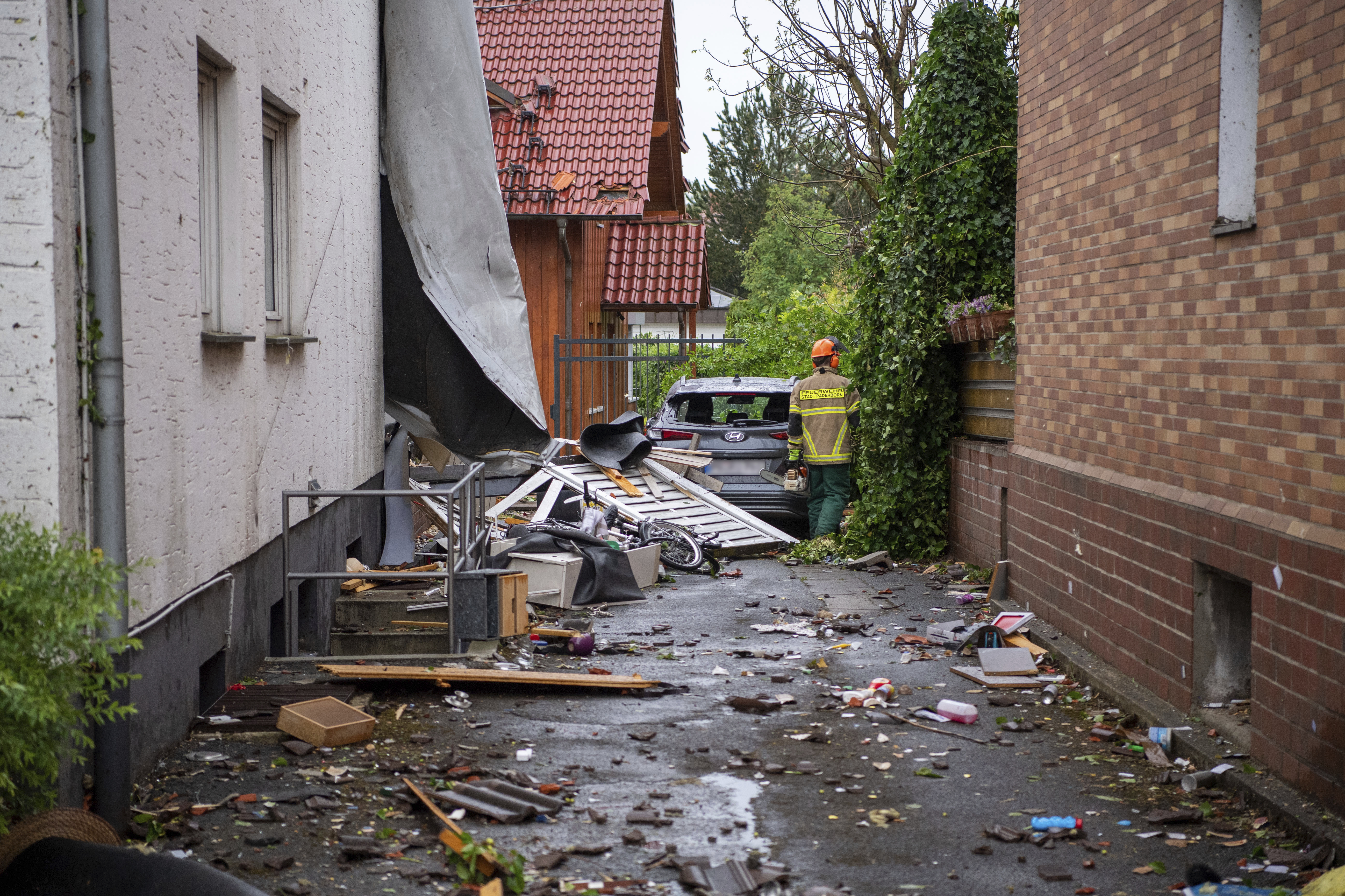 A fire fighter is seen near a damaged car after a suspected tornado in Lippstadt, Germany, Friday, May 20, 2022. (Friso Gentsch/dpa via AP)