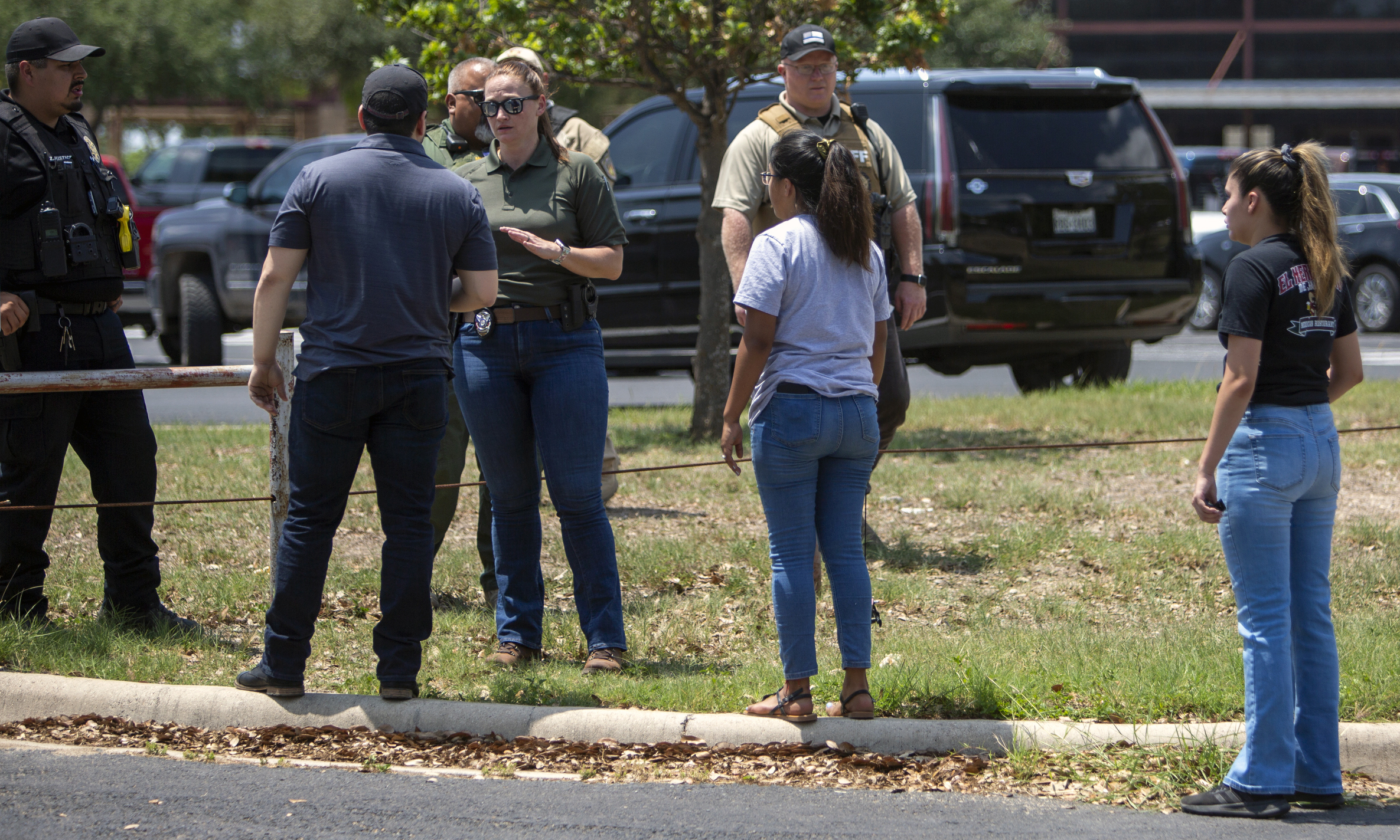 A law enforcement officer speaks with people outside Uvalde High School after shooting a was reported earlier in the day at Robb Elementary School, Tuesday, May 24, 2022, in Uvalde, Texas. (William Luther/The San Antonio Express-News via AP)