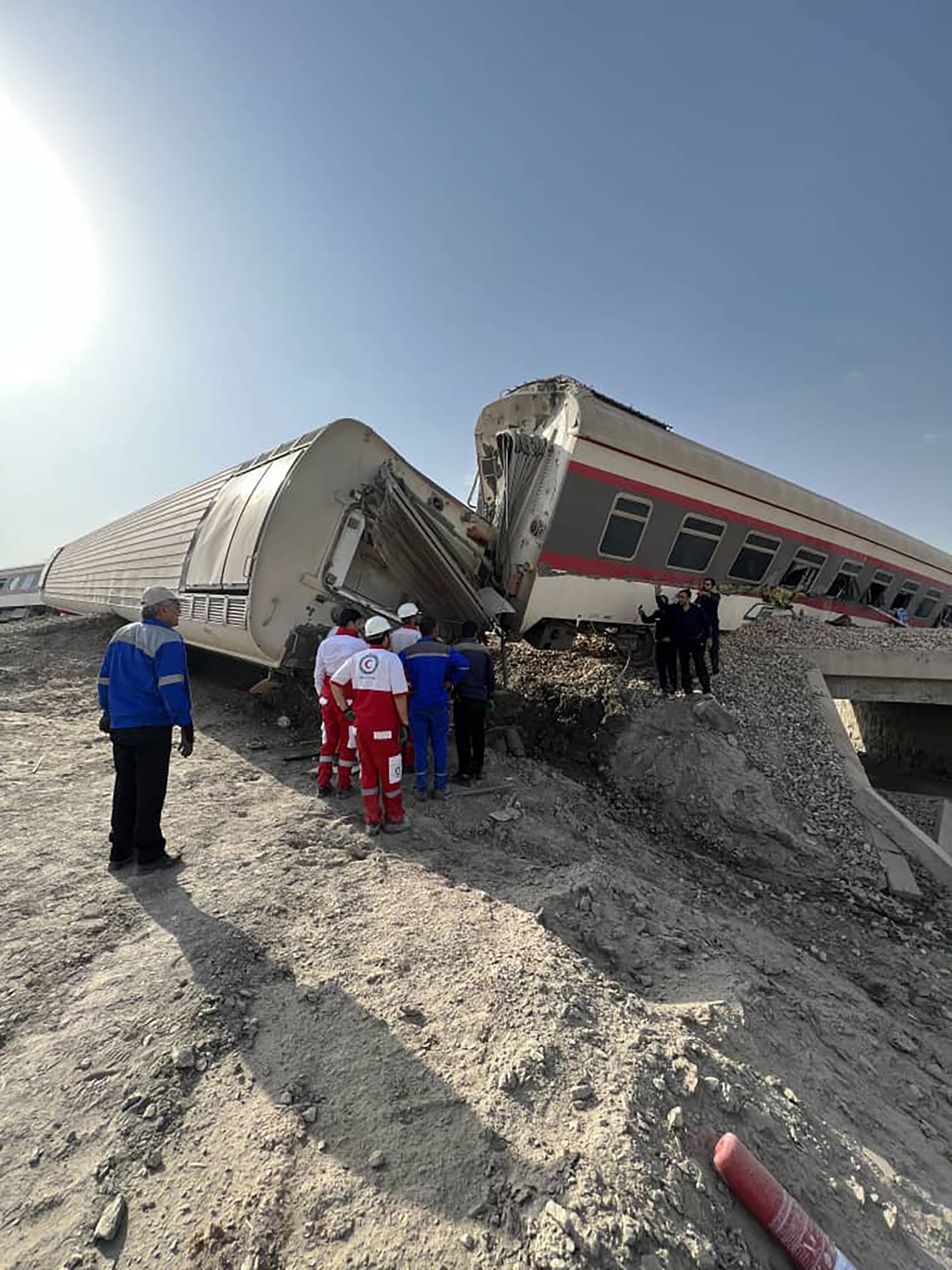 In this photo provided by Iranian Red Crescent Society, rescuers work at the scene where a passenger train partially derailed near the desert city of Tabas in eastern Iran, Wednesday, June 8, 2022. (Iranian Red Crescent Society via AP)