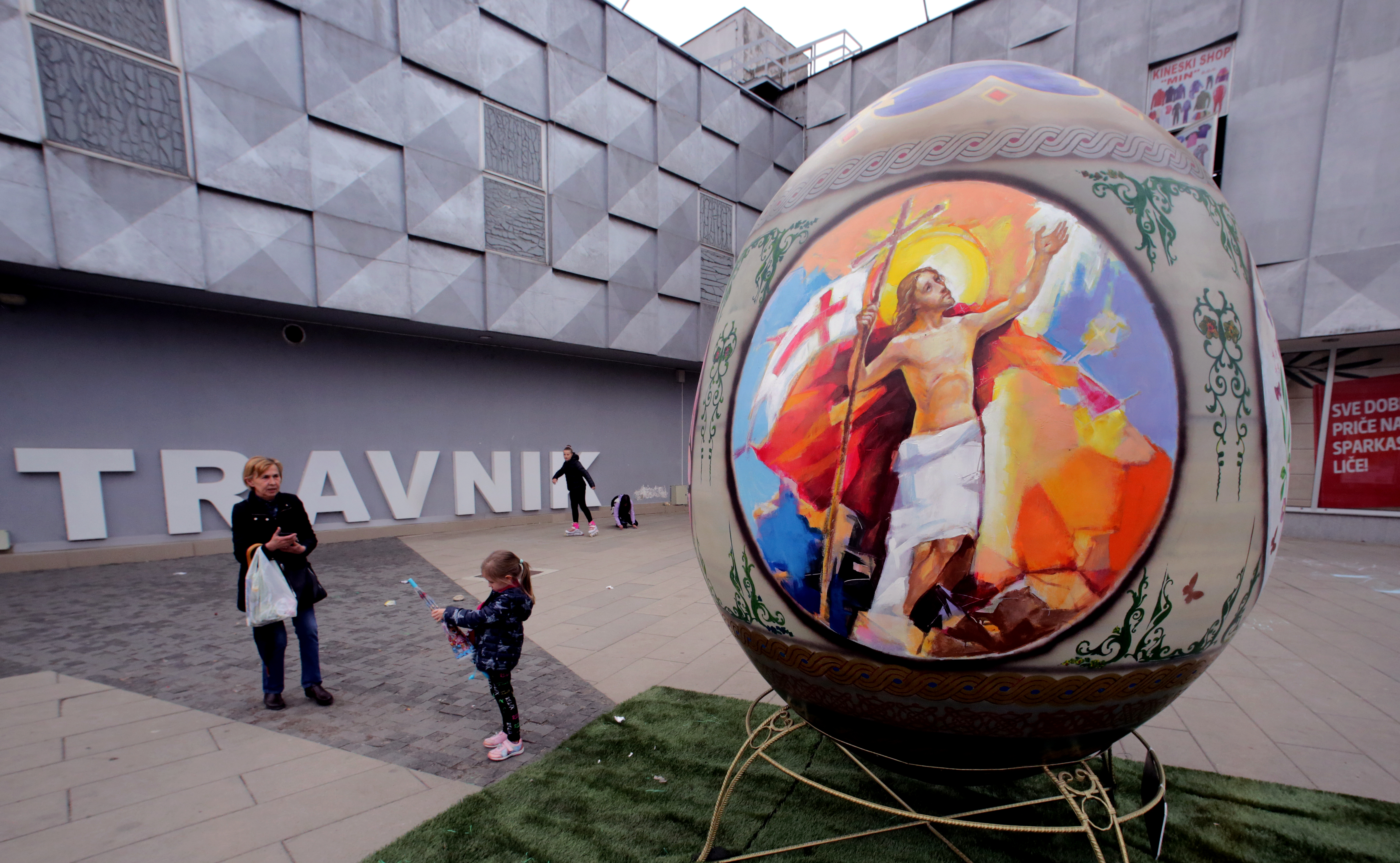 epa09893196 people walk past a giant Easter egg placed in the central square of Travnik, Bosnia and Herzegovina, 16 April 2022. The 2.64-meter-tall Easter egg was painted by several Bosnian artists.  EPA-EFE/FEHIM DEMIR