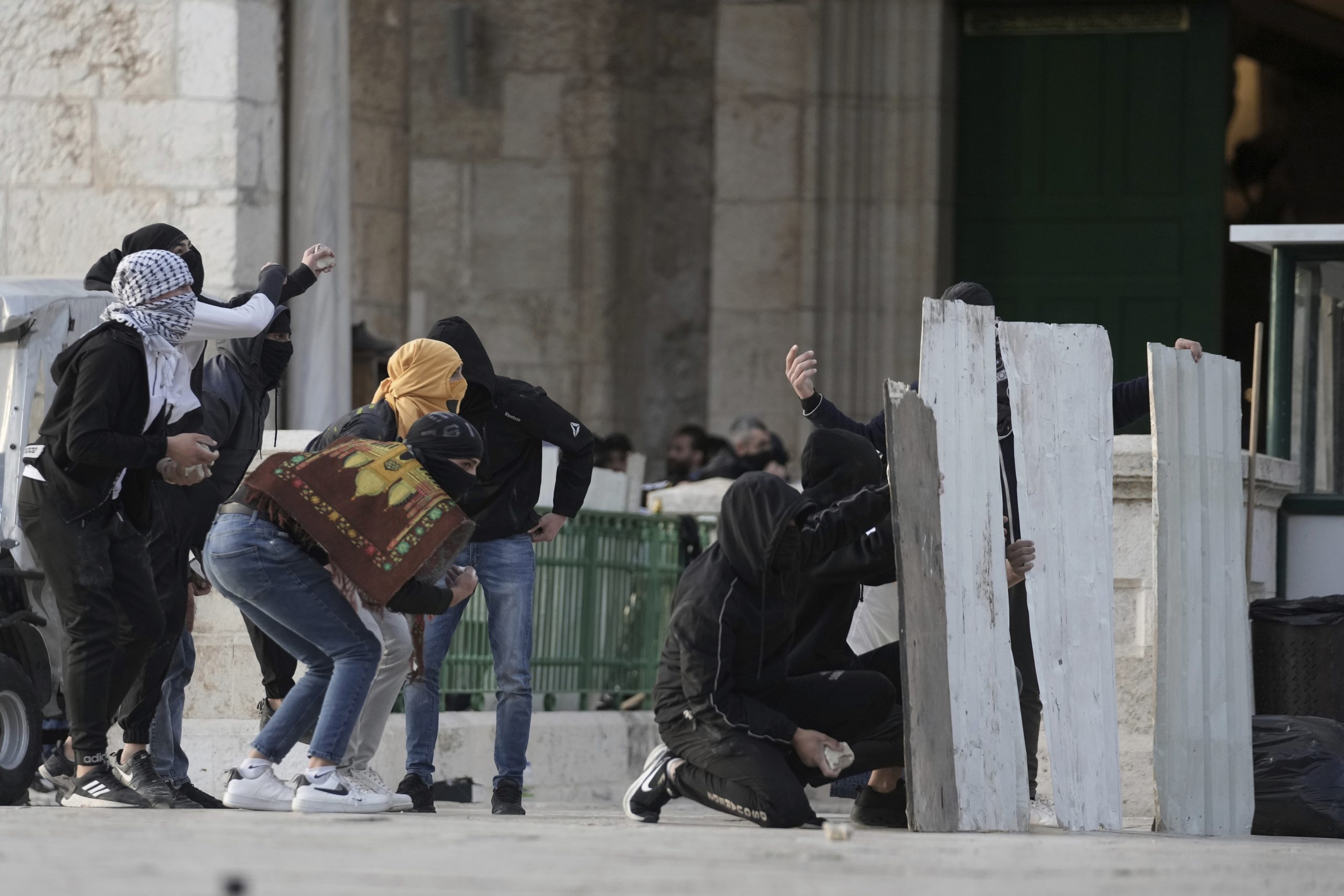 Palestinian protesters use makeshift shields during clashes with Israeli police at the Al Aqsa Mosque compound in Jerusalem's Old City, Friday, April 22, 2022. (AP Photo/Mahmoud Illean)