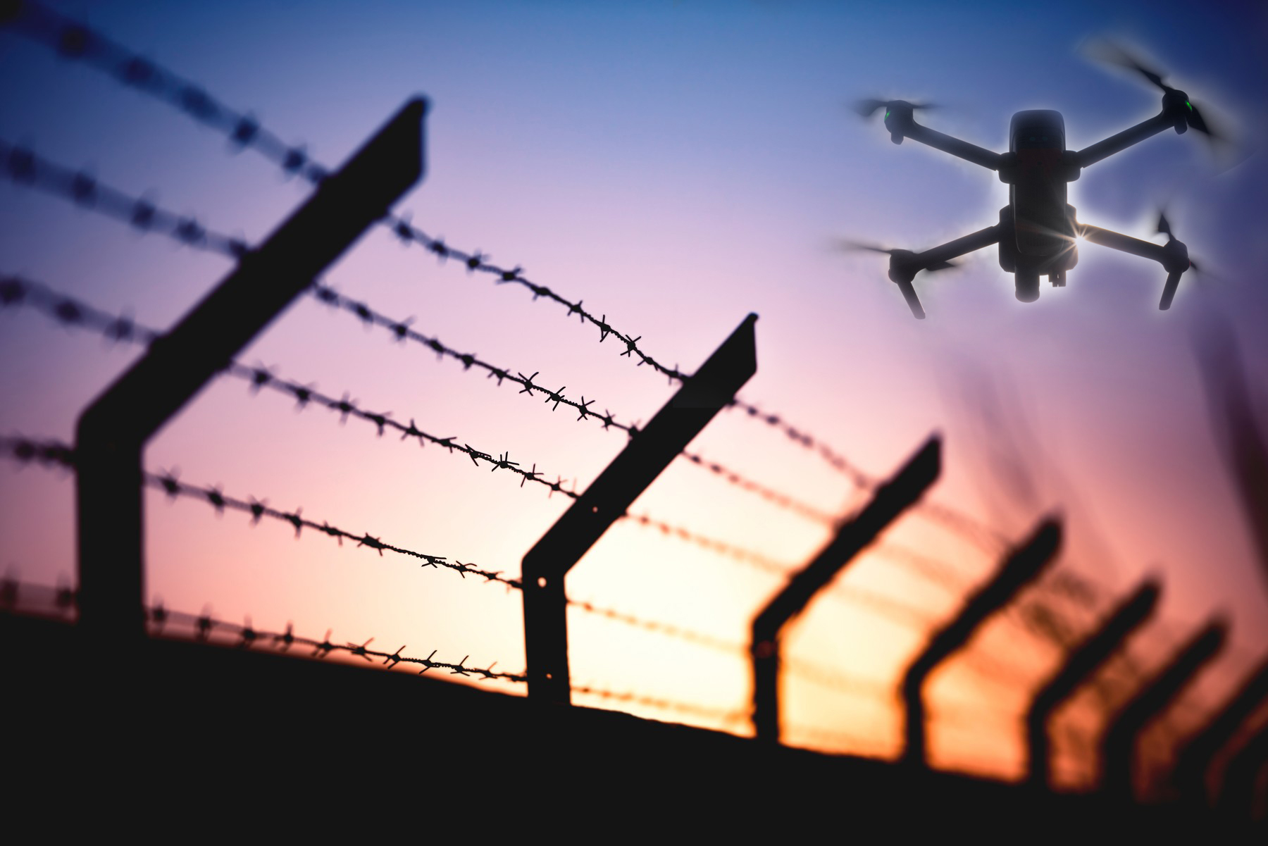 Silhouette of barbed wire fence dron zatvor