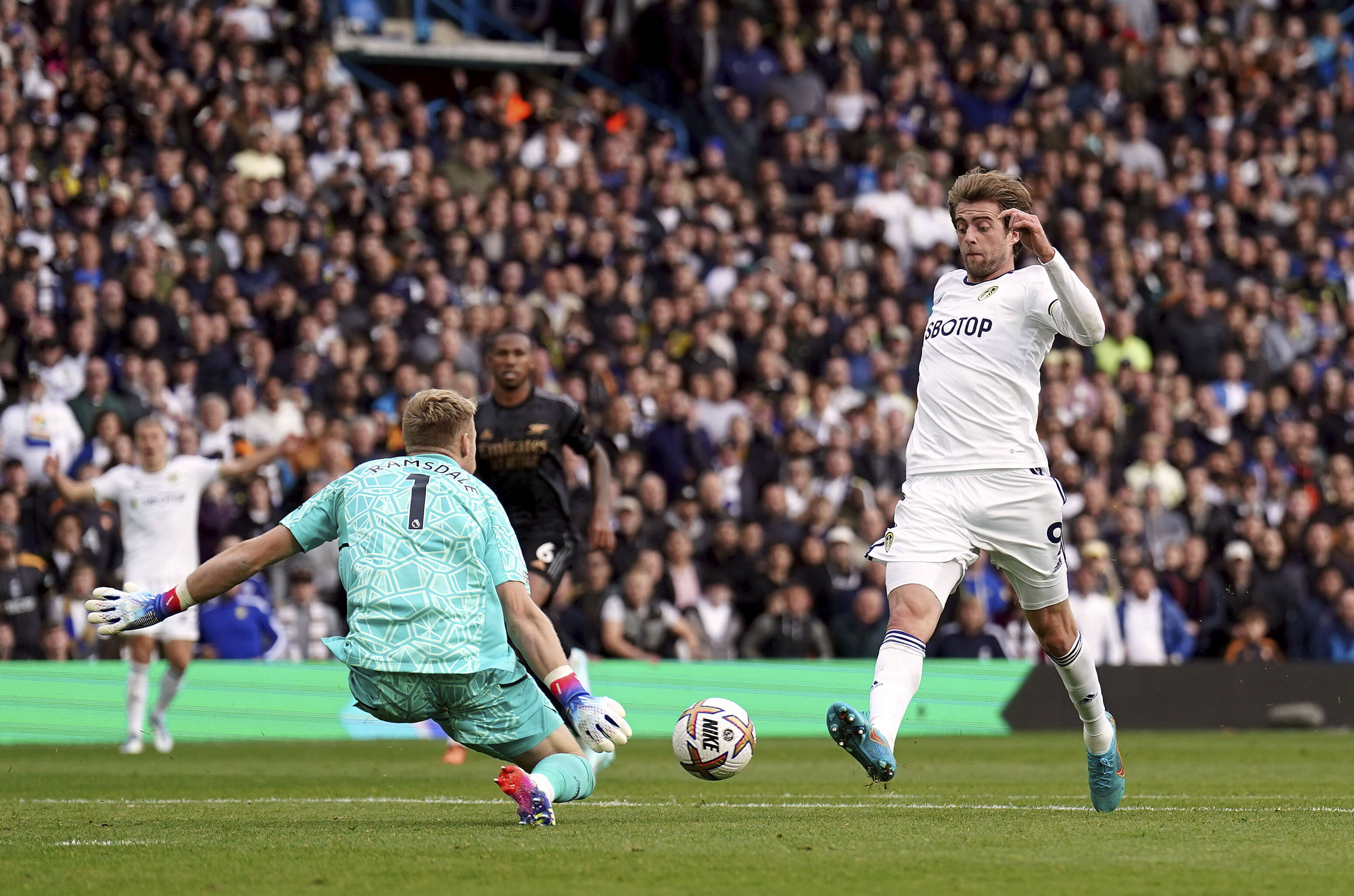 Arsenal goalkeeper Aaron Ramsdale saves from Leeds United's Patrick Bamford during the Premier League match betweem Leeds United and Arsenal at Elland Road in Leeds, Britain, Sunday Oct. 16, 2022. (Tim Goode/PA via AP)