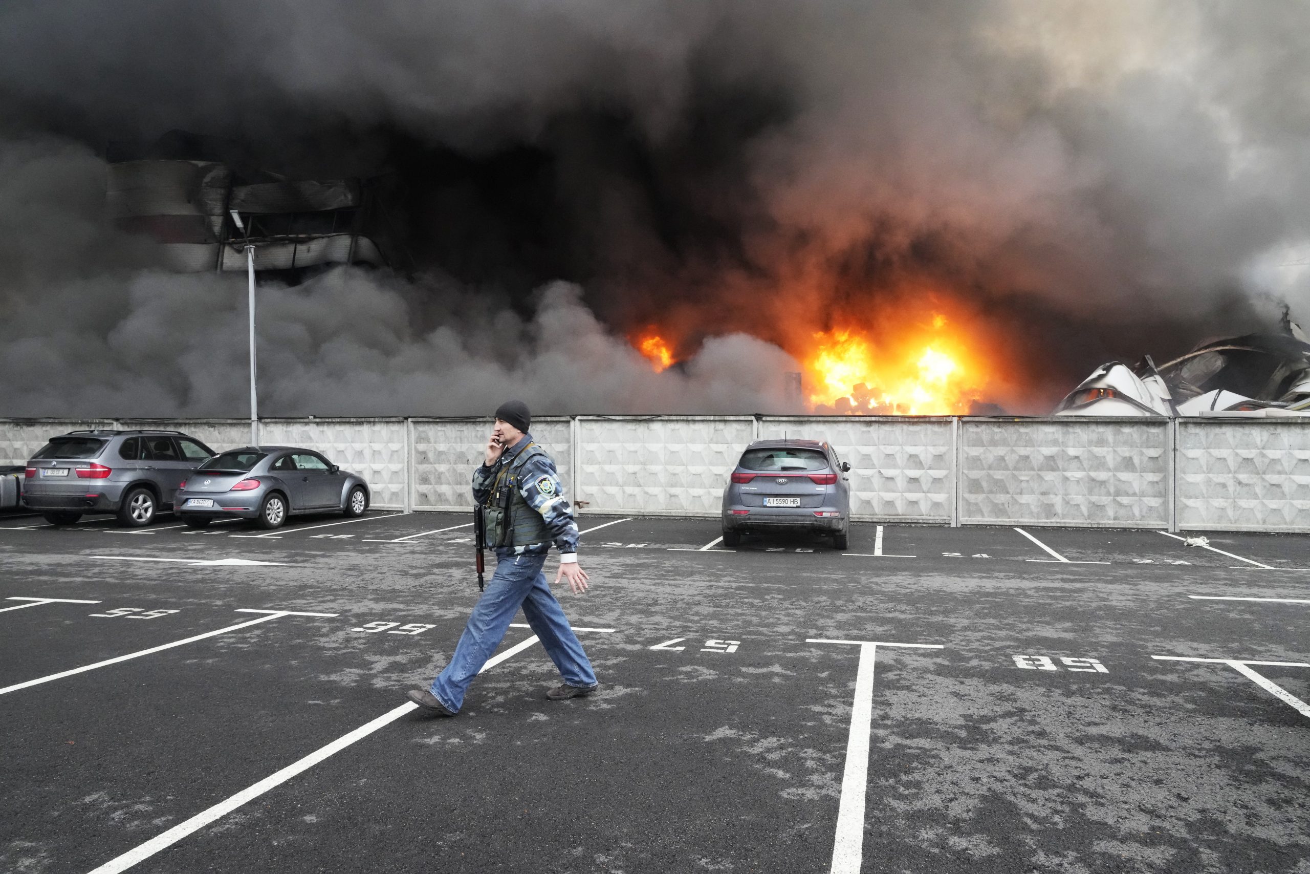 FILE - A Ukrainian serviceman walks past as fire and smoke rises over a damaged logistic center after shelling in Kyiv, Ukraine, March 3, 2022.  (AP Photo/Efrem Lukatsky, File)