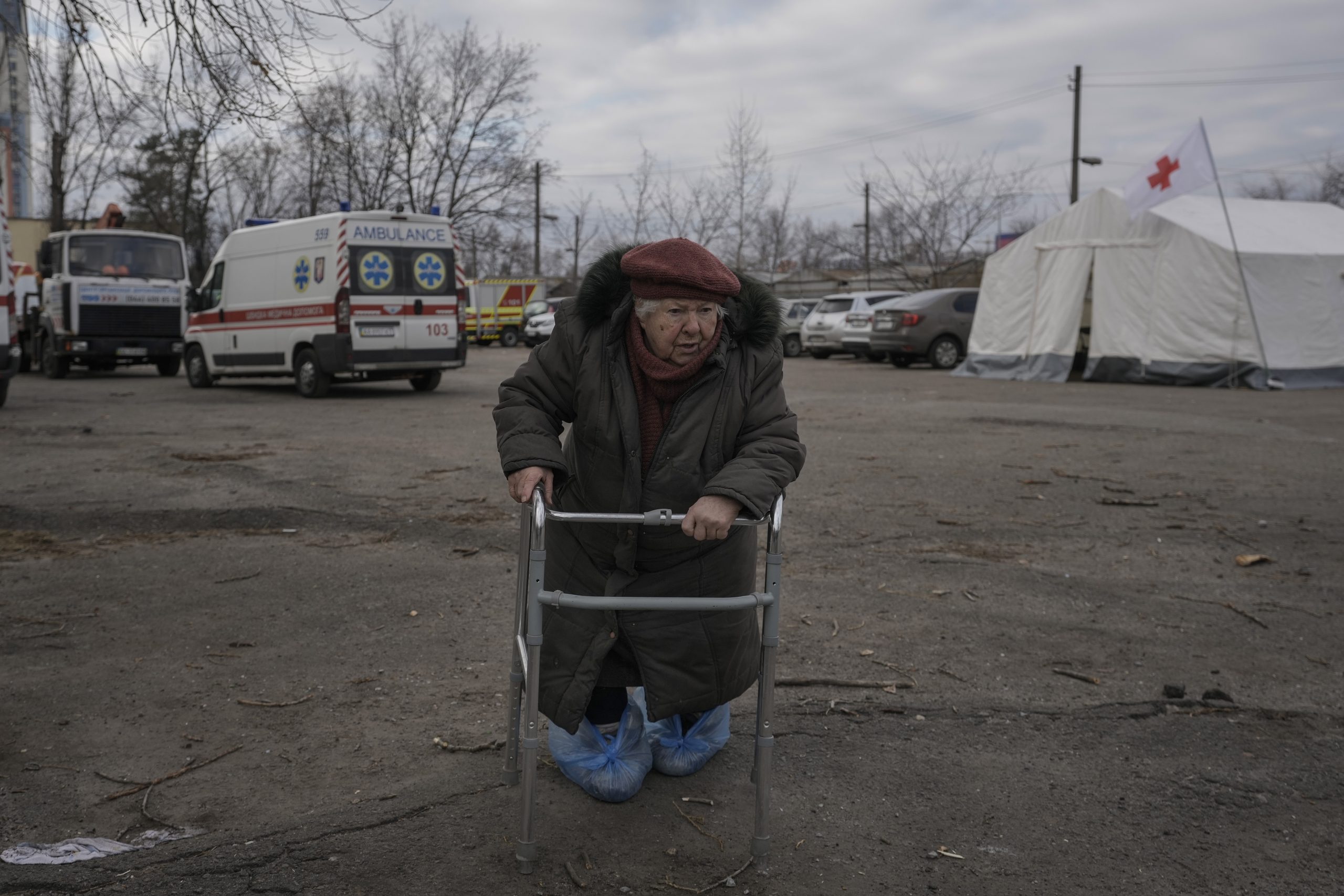 A local resident looks at Ukrainian firefighters working in an apartment building after it was hit by artillery shelling in Kyiv, Ukraine, Monday, March 14, 2022. (AP Photo/Vadim Ghirda)