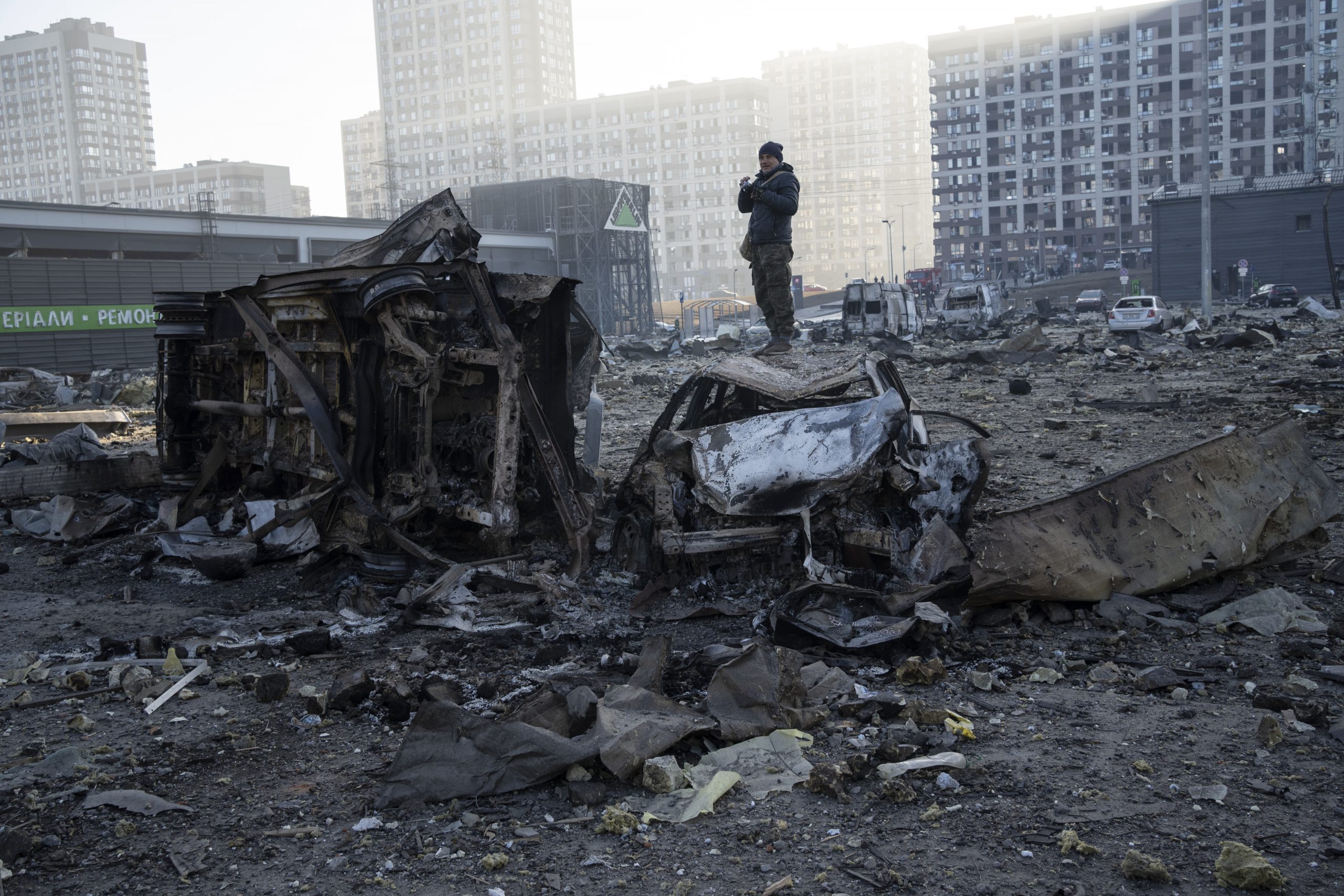 A man stands on top of a destroyed car amid the destruction caused after shelling of a shopping center, in Kyiv, Ukraine, Monday, March 21, 2022. (AP Photo/ (AP Photo/Rodrigo Abd)