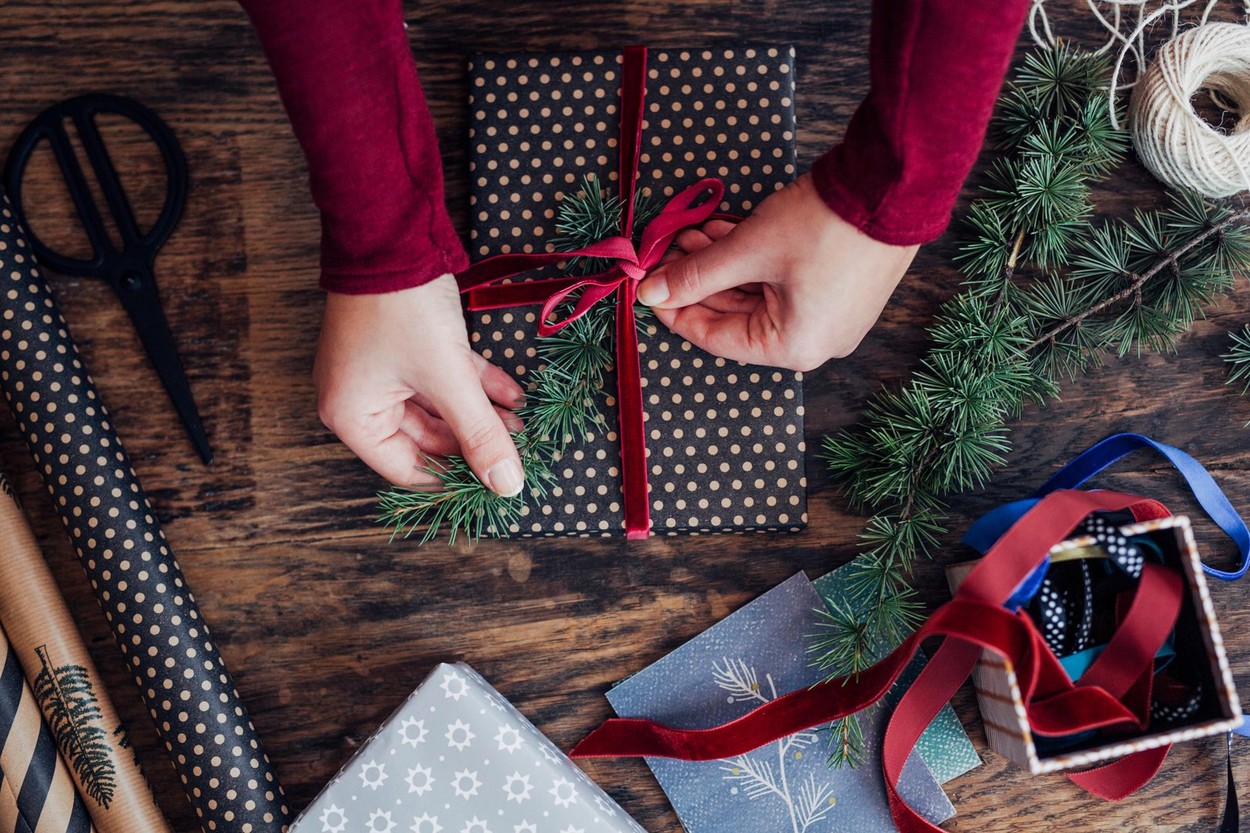 Woman Tying Ribbon on Christmas Present
