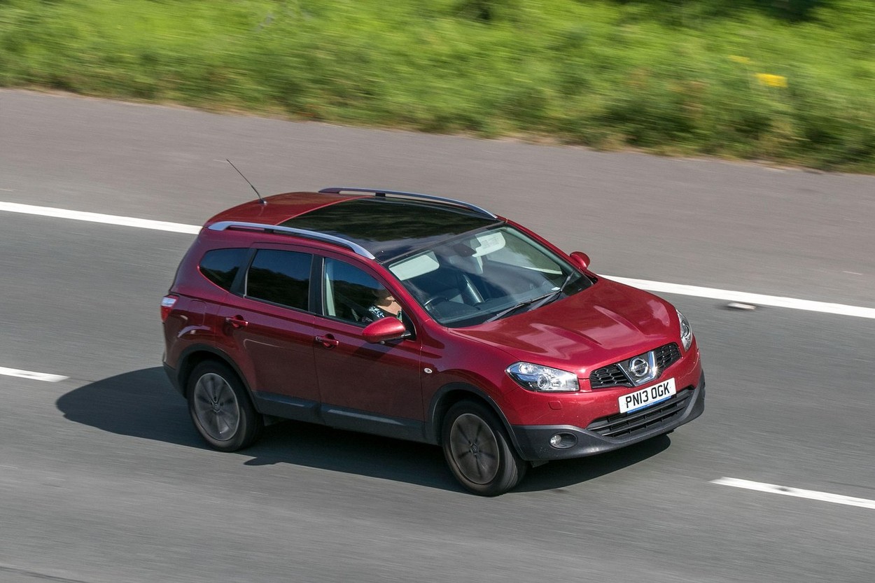 2013 Nissan Qashqai Tekna + 2 Dci Red Car SUV Diesel driving on the M6 motorway near Preston in Lancashire, UK.