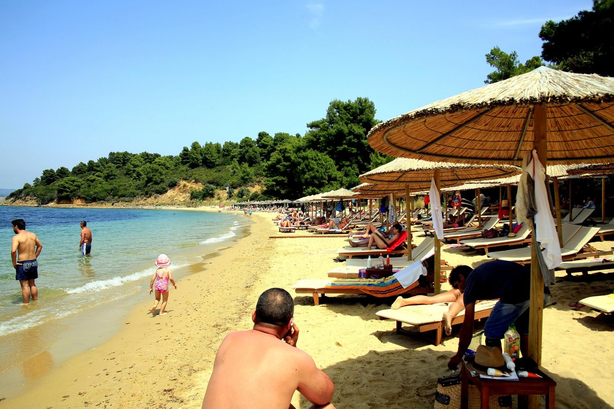 Families enjoying the sun, sea and sand on Agia Eleni beach on the Island of Skiathos in the Greek Islands, Greece.