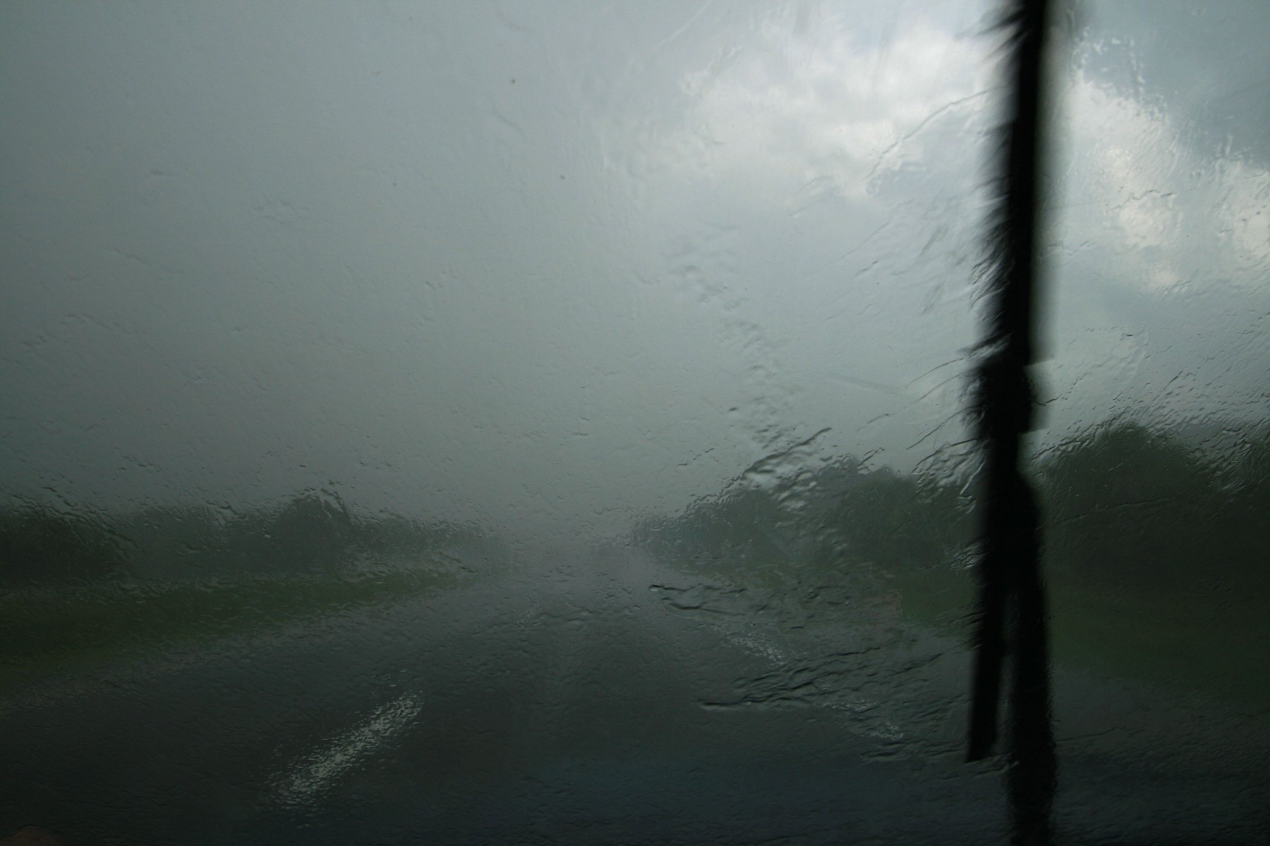 rainy windshield with wiper blade pushing torrential downpour across it but still very poor visibility