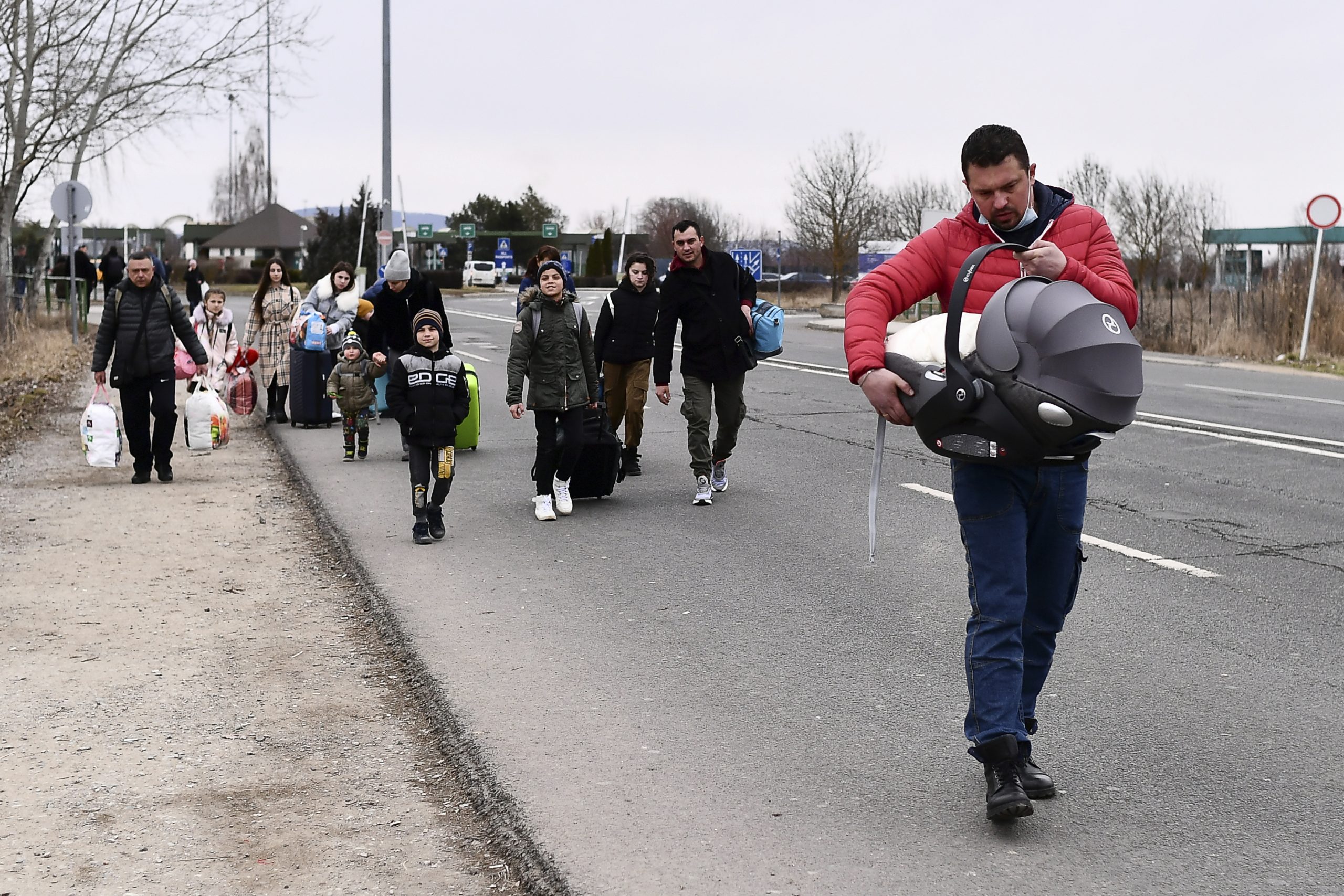 Refugees walk to a checkpoint run by local volunteers after arriving from Ukraine, crossing the border in Beregsurany, Hungary, Saturday, Feb 26, 2022. Hungary has extended legal protection to those fleeing the Russian invasion. (AP Photo/Anna Szilagyi)