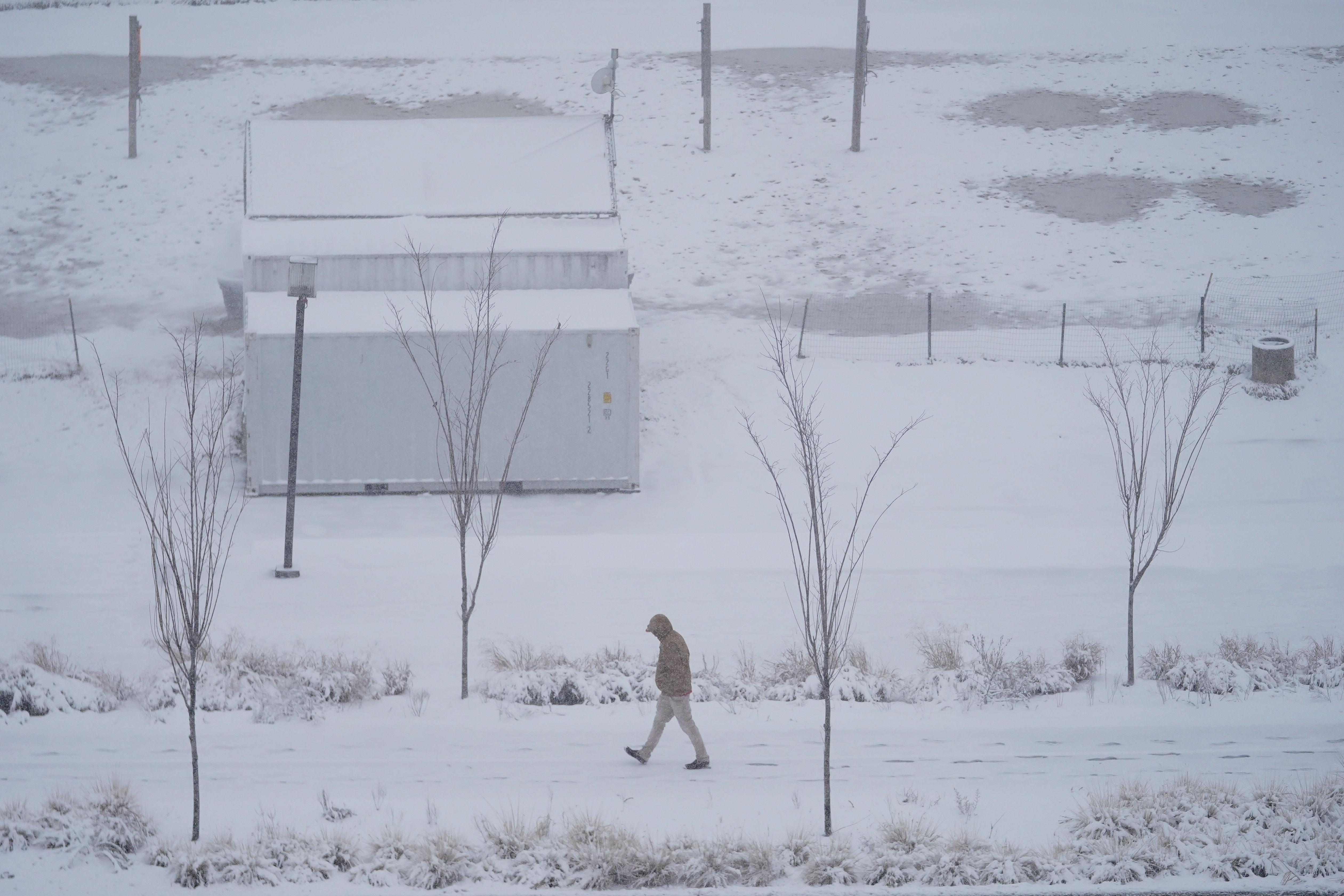 A man strolls on a snow-covered path along the Inner Harbor, Monday, Jan. 3, 2022, in Baltimore. (AP Photo/Julio Cortez)