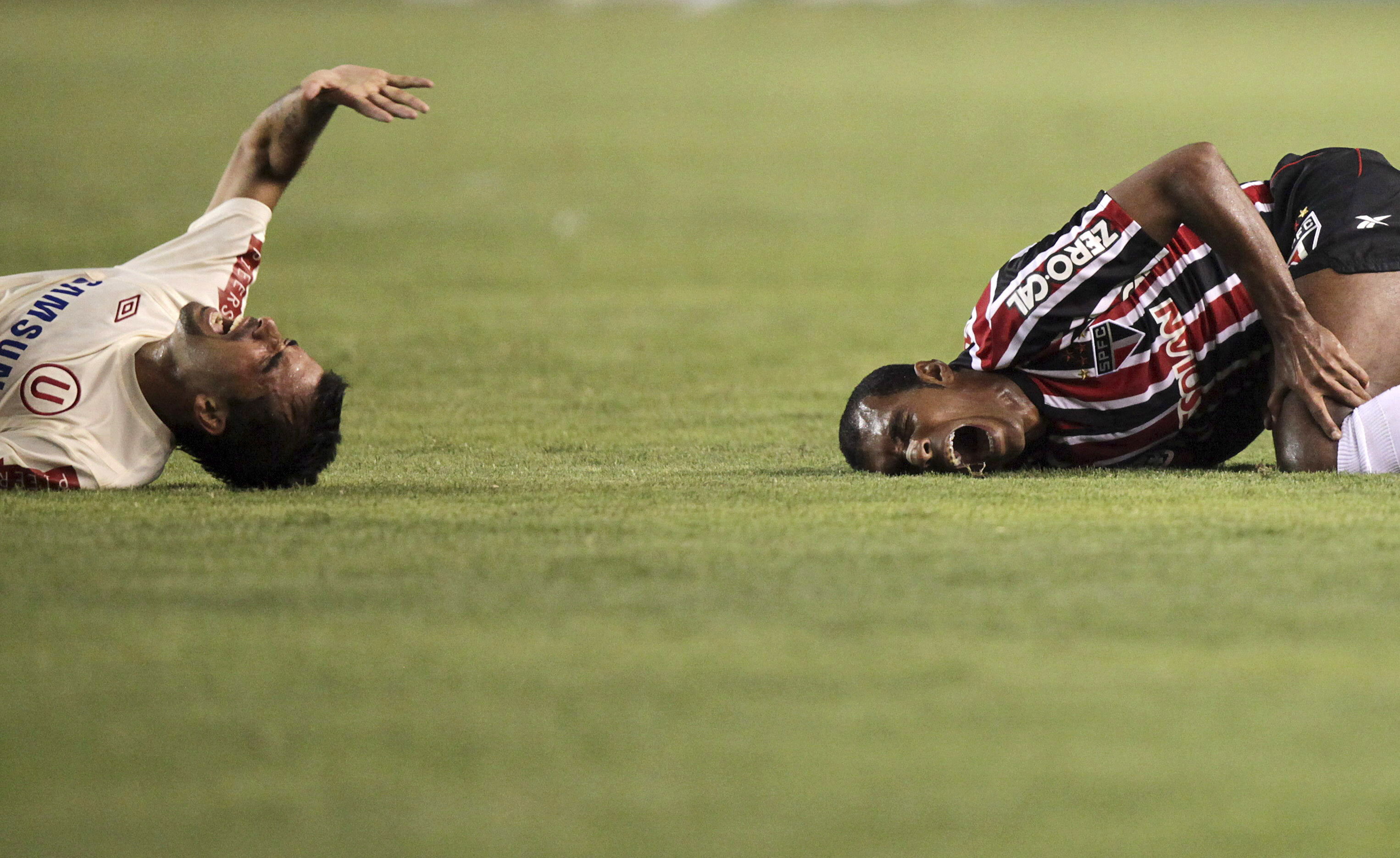 epa02135682 Sao Paulo's Richarlyson (R) and Universitario's Renzo Revoredo (L) react after colliding during their Libertadores Cup soccer match at Monumental stadium in Lima, Peru, 28 April 2010.  EPA/PAOLO AGUILAR