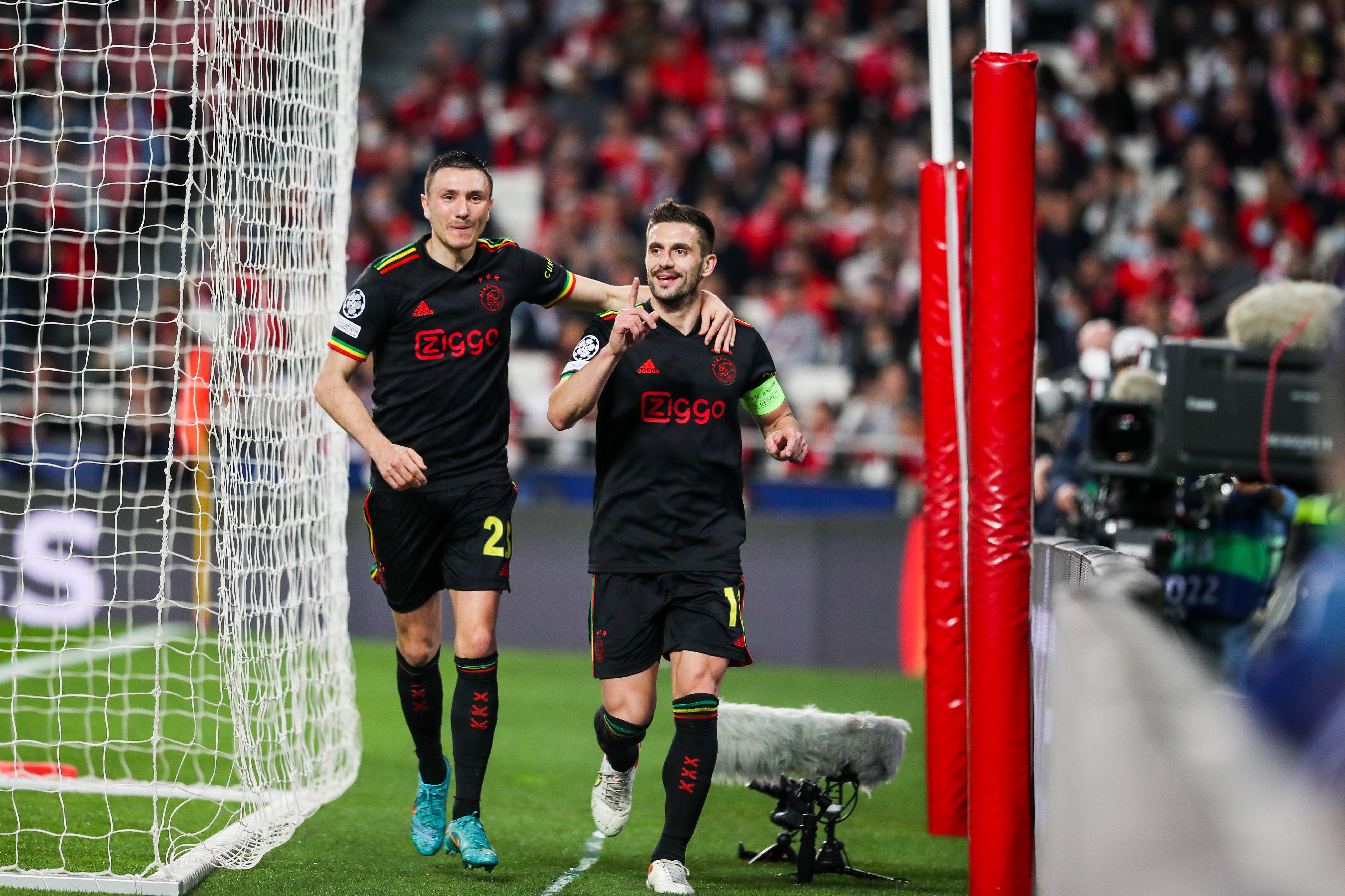 epa09779645 FC Ajax´s player Dusan Tadic (R) celebrates after scoring a goal against Benfica during the UEFA Champions League knockout round play-offs first leg soccer match, at Luz Stadium, in Lisbon, 23 February 2022.  EPA-EFE/JOSE SENA GOULAO
