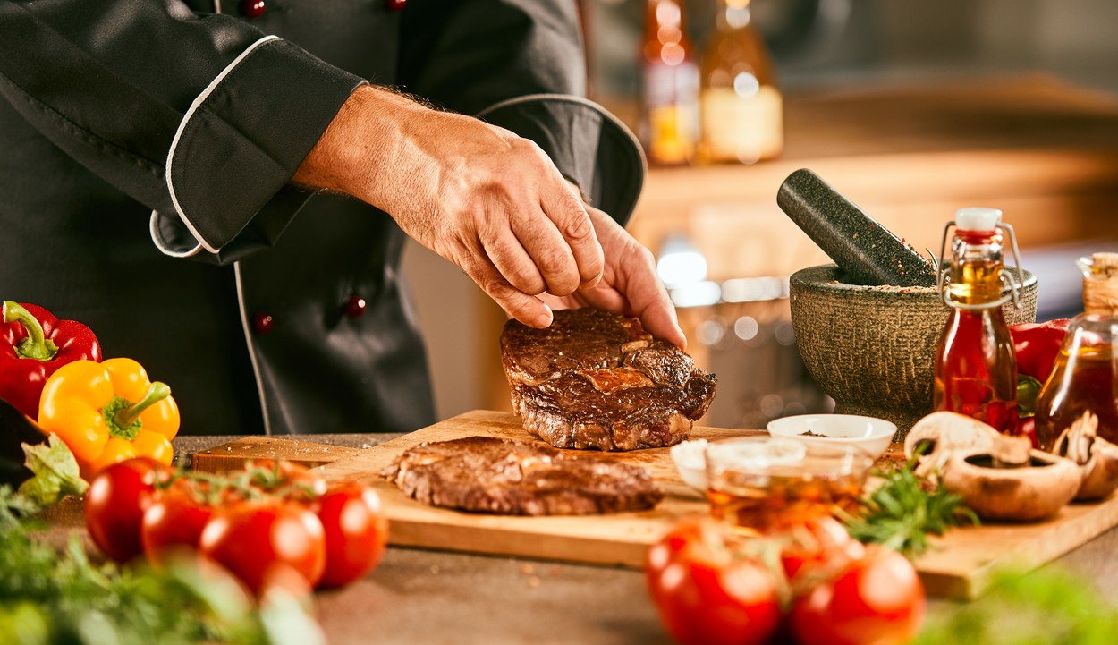 Chef seasoning a raw steak for grilling surrounded by fresh ingredients and vegetables in a close up on his hands,Image: 528488676, License: Royalty-free, Restrictions: , Model Release: no, Credit line: Daniel Reiter / Panthermedia / Profimedia