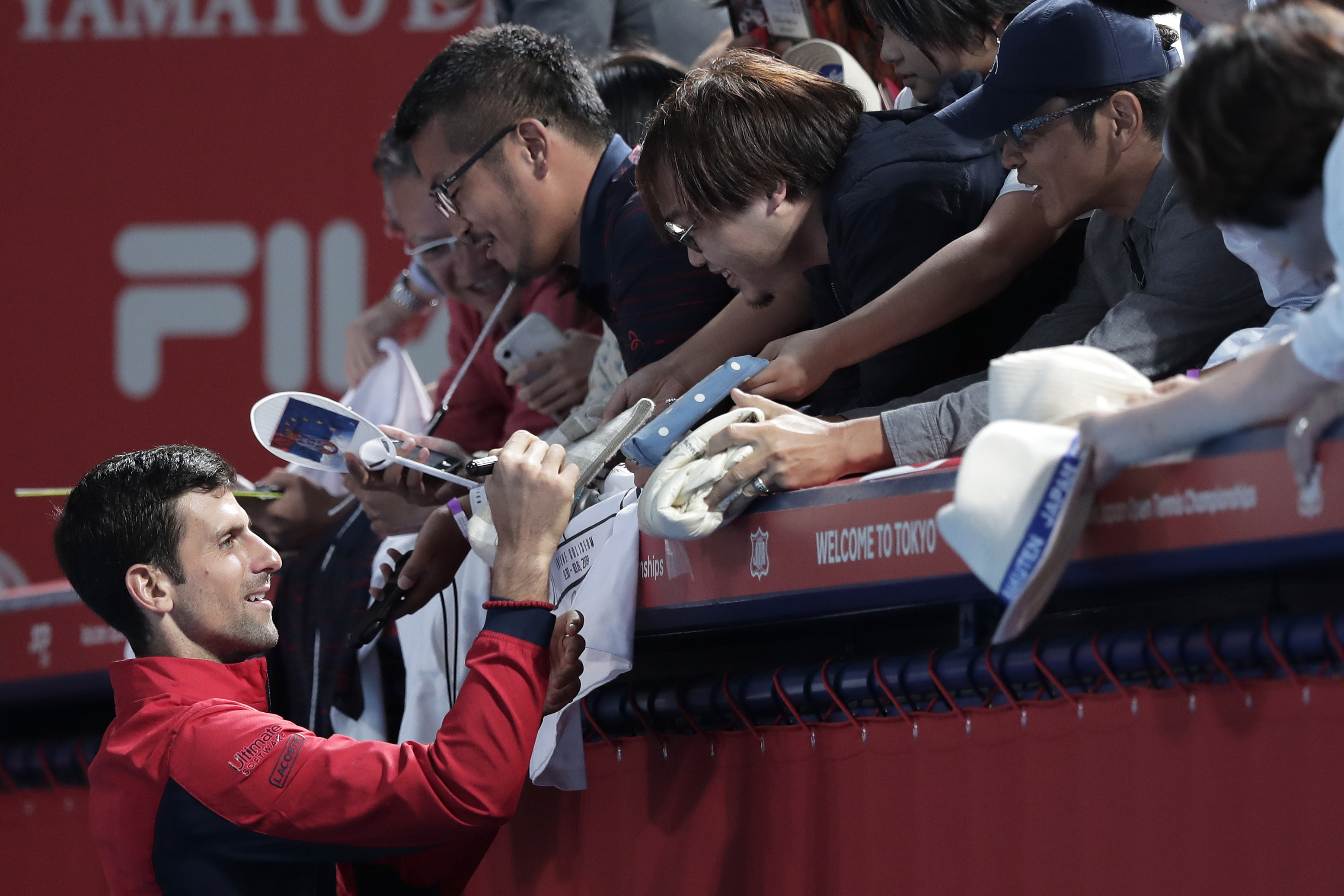 epa07900458 Novak Djokovic (L) of Serbia signs autographs to fans after winning the men's singles final match against John Millman of Australia at the Japan Open Tennis Championships in Tokyo, Japan, 06 October 2019.  EPA-EFE/KIYOSHI OTA