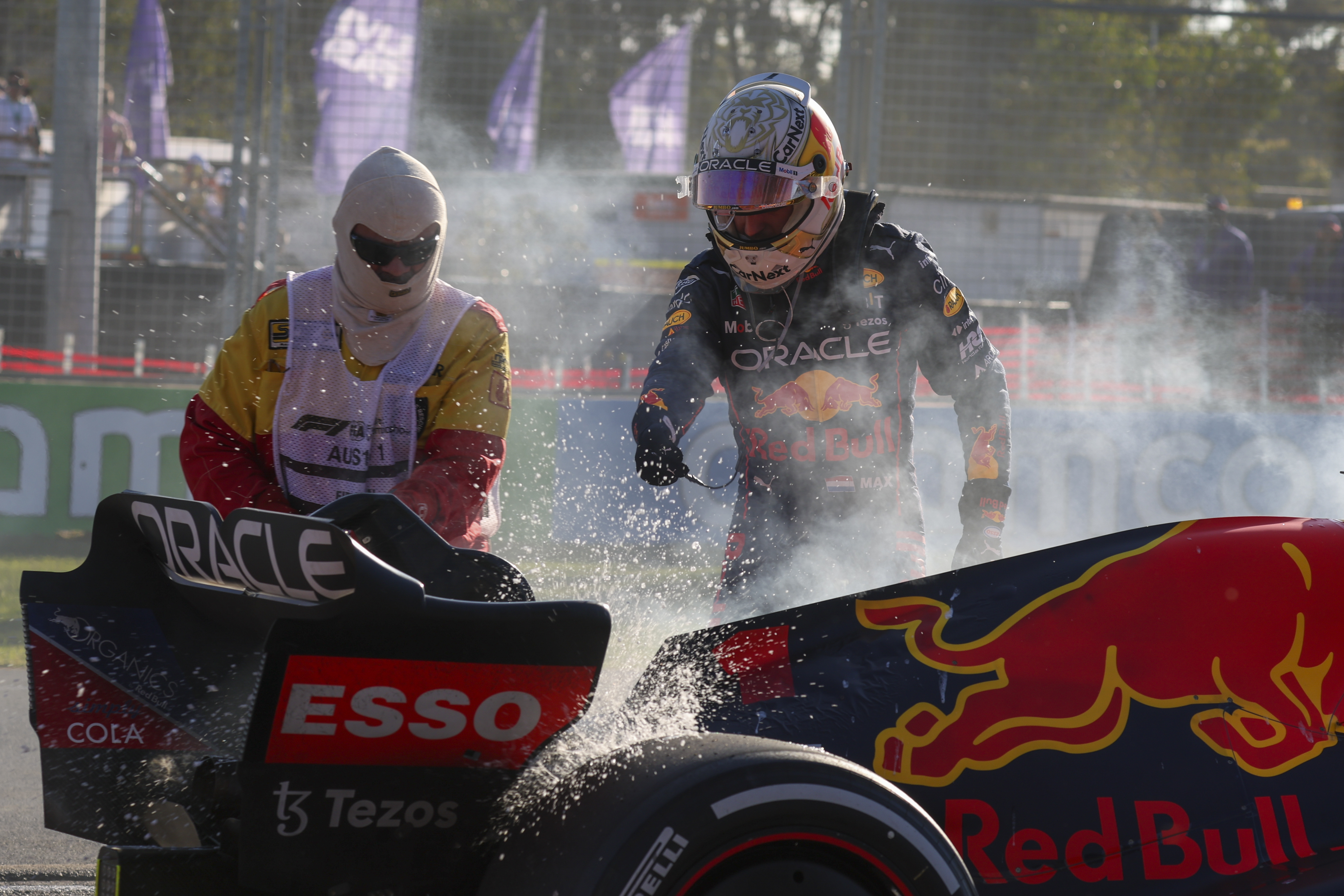 Red Bull driver Max Verstappen, right, of the Netherlands watches as a track marshal extinguishes a fire in his car during the Australian Formula One Grand Prix in Melbourne, Australia, Sunday, April 10, 2022. (AP Photo/Asanka Brendon Ratnayake)