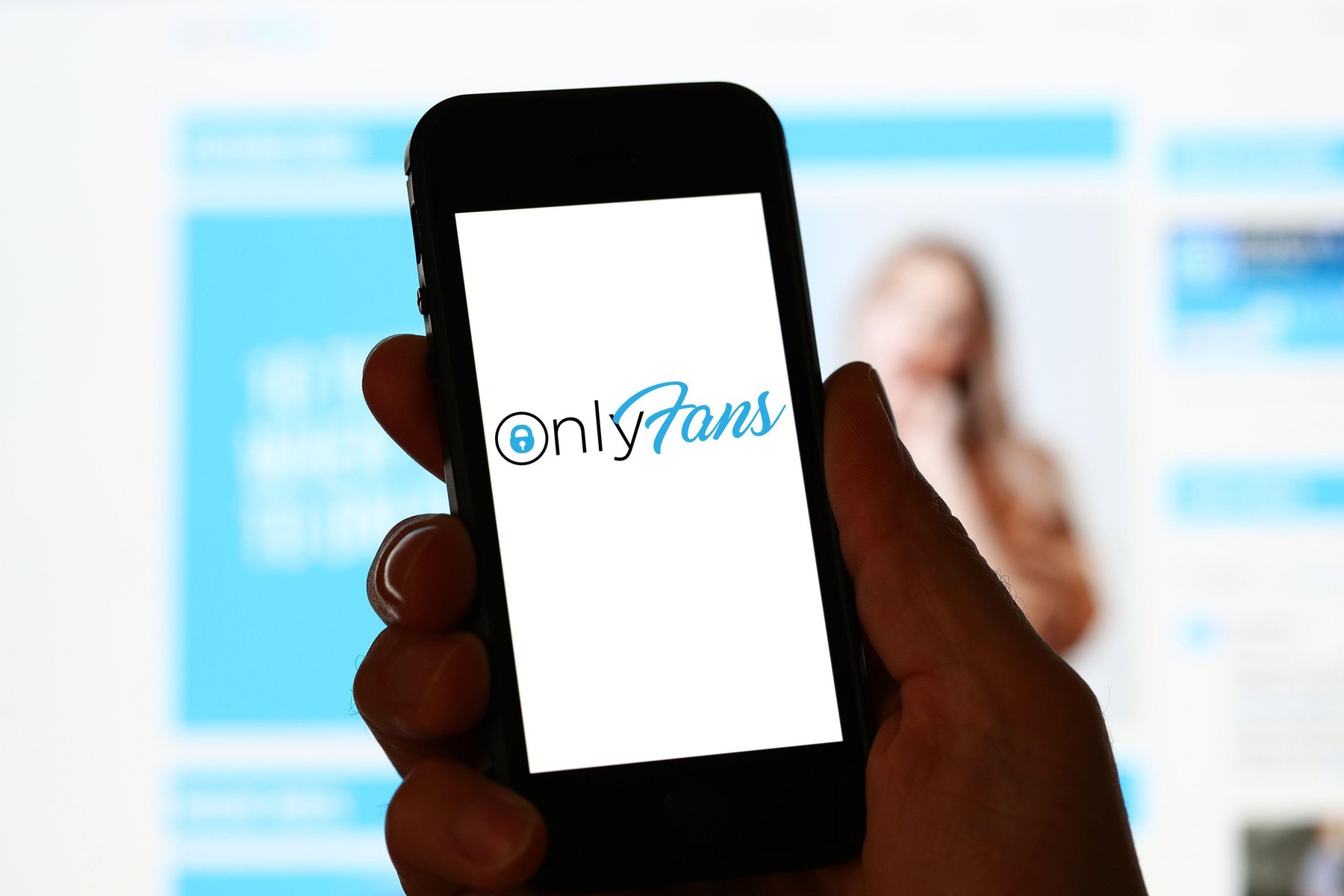 A man looking at OnlyFans website on a computer and mobile phone