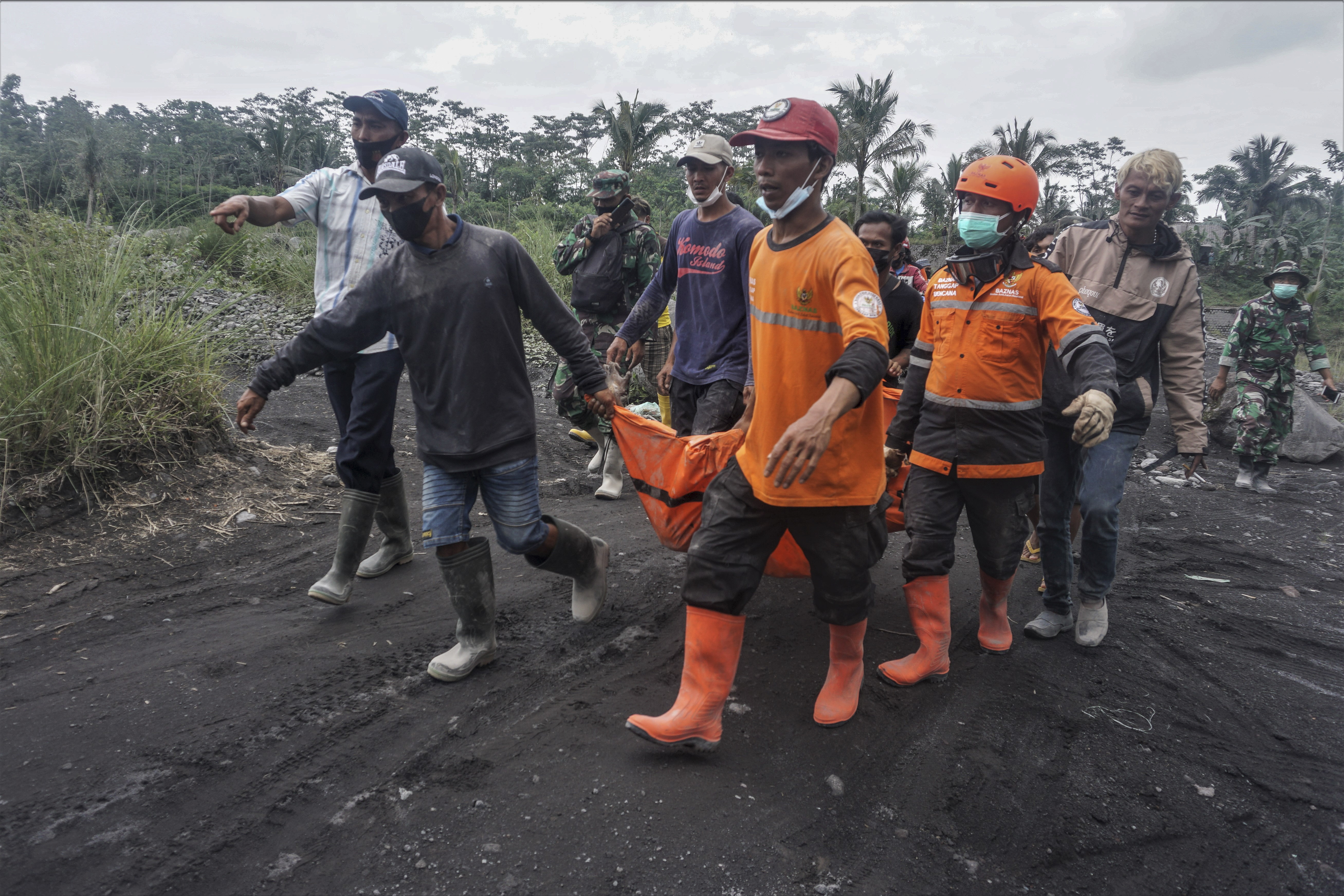 epa09622890 Rescuers carry the body of a victim of the Mount Semeru eruption in a village in Lumajang, East Java, Indonesia, 05 December 2021. The volcano erupted on 04 December leaving a number of people killed and missing.  EPA-EFE/AMMAR