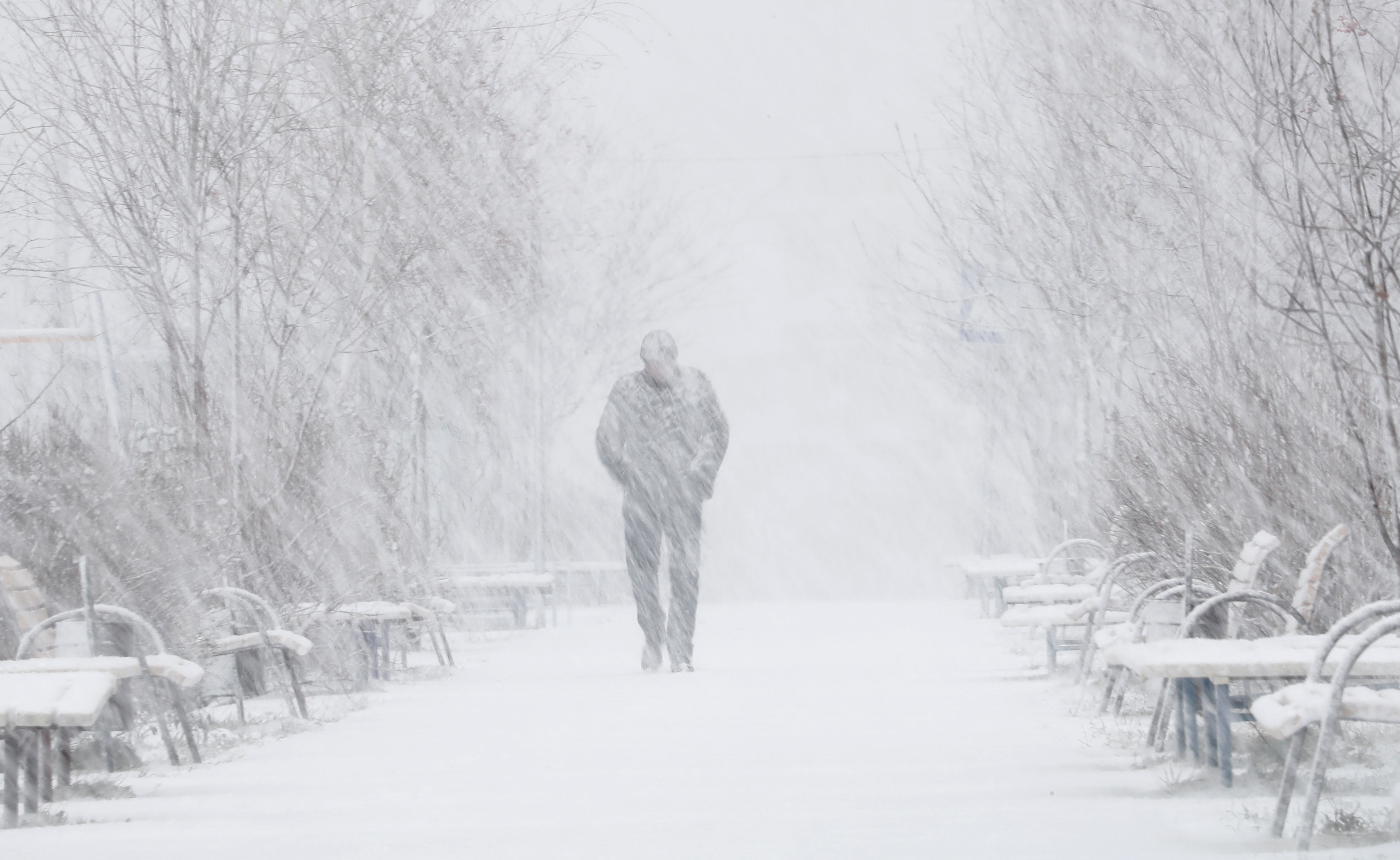 epa09578141 A man walks on a street during a snowfall in the town of Podolsk, outside Moscow, Russia, 12 November 2021. The temperature exceeded 2 degrees celsius in the Moscow region.  EPA-EFE/MAXIM SHIPENKOV