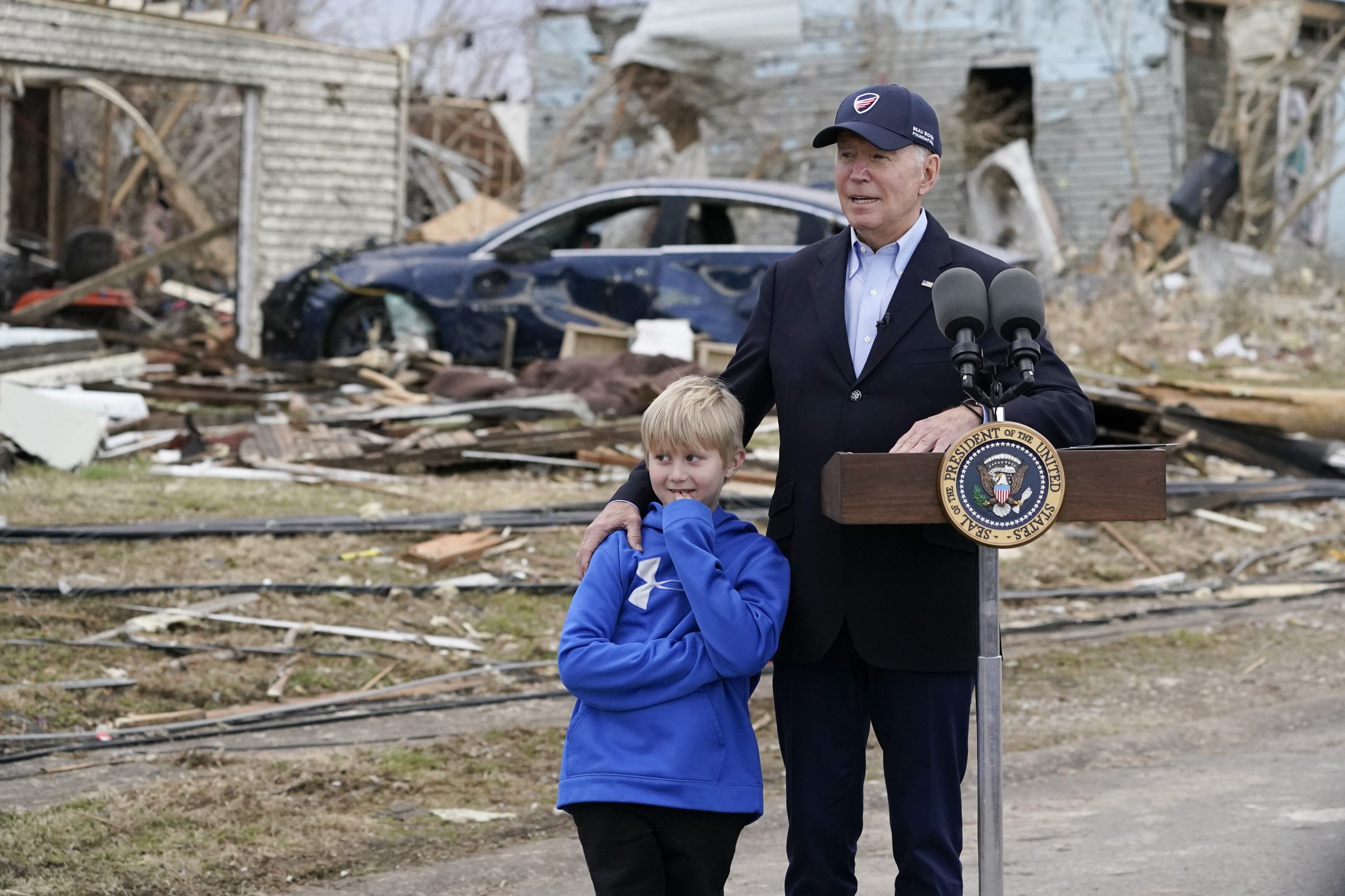 President Joe Biden stands with Dane Maddox, 7, as he speaks after surveying storm damage from tornadoes and extreme weather in Dawson Springs, Ky., Wednesday, Dec. 15, 2021. (AP Photo/Andrew Harnik)